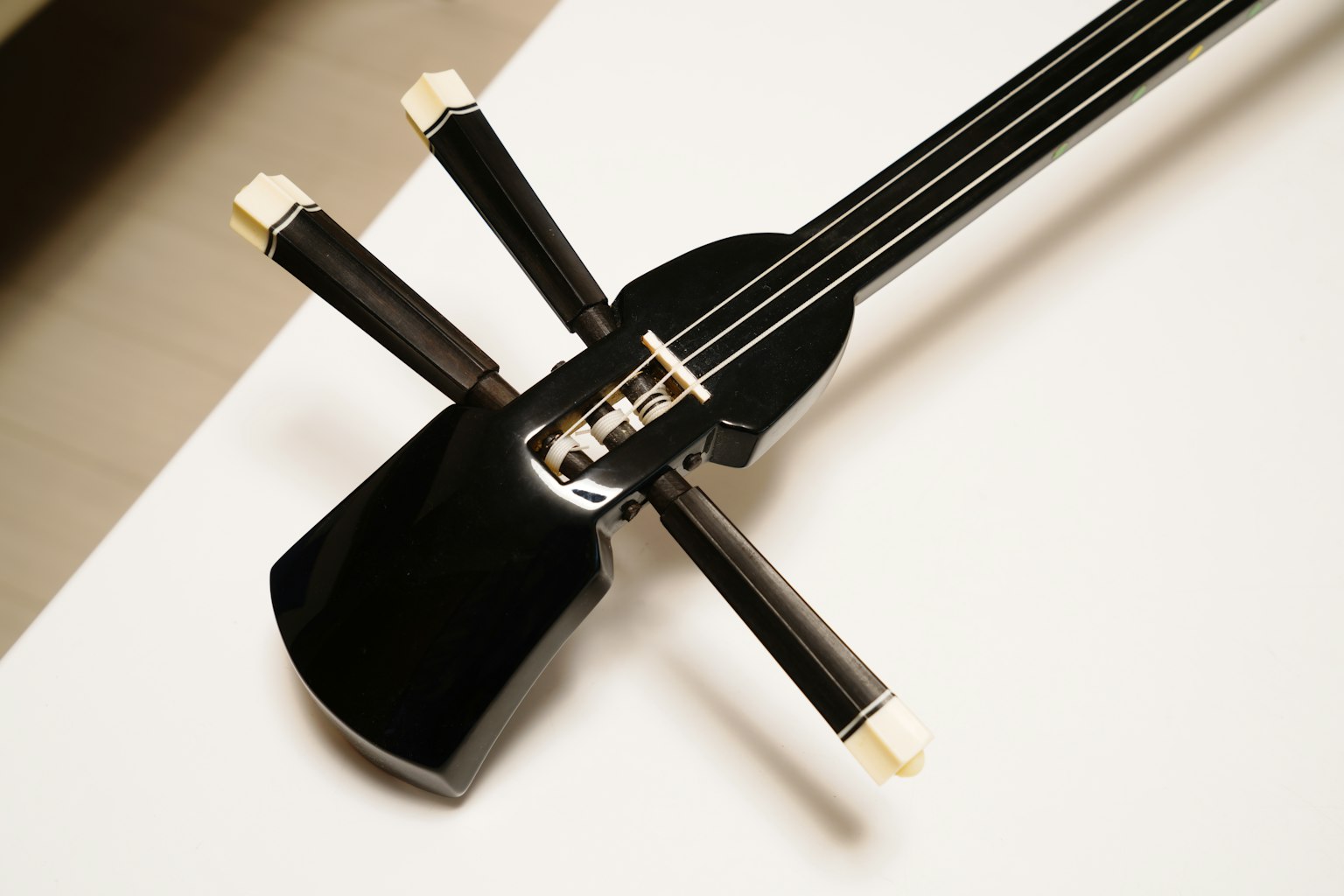 Cận cảnh của một nhạc cụ dây màu đen với ba dây và các đặc điểm thân độc đáo
