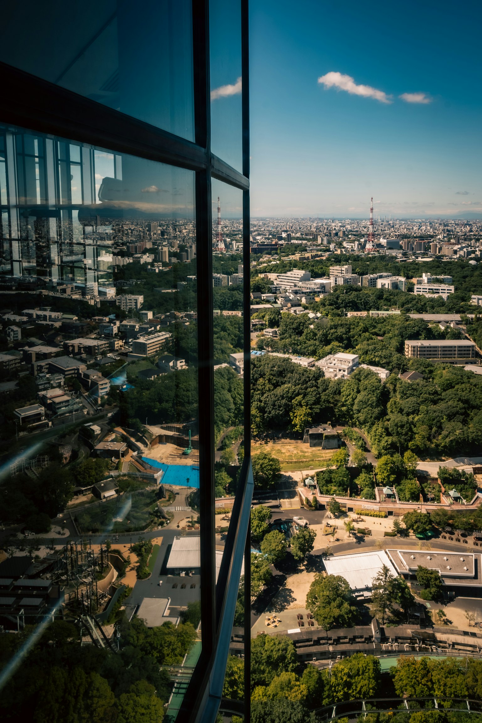 City view from a high-rise window featuring green spaces and buildings