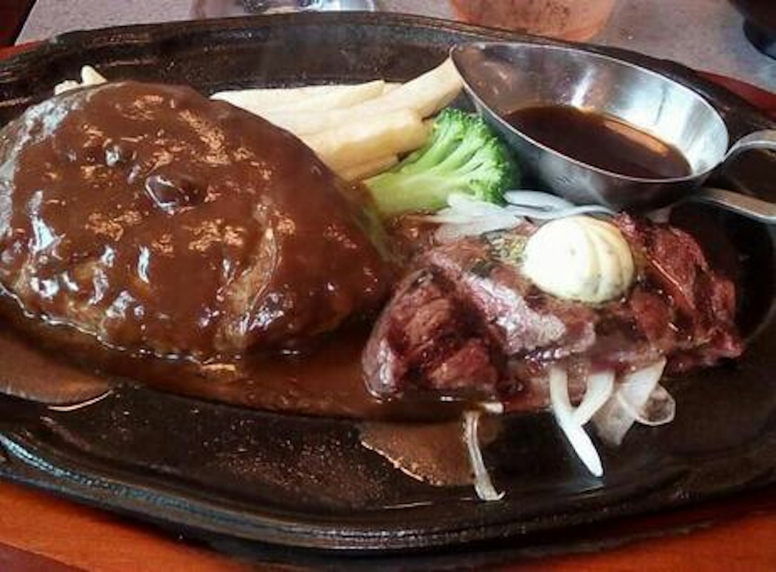 Una bandeja caliente con hamburguesa y bistec a la parrilla con verduras y salsa