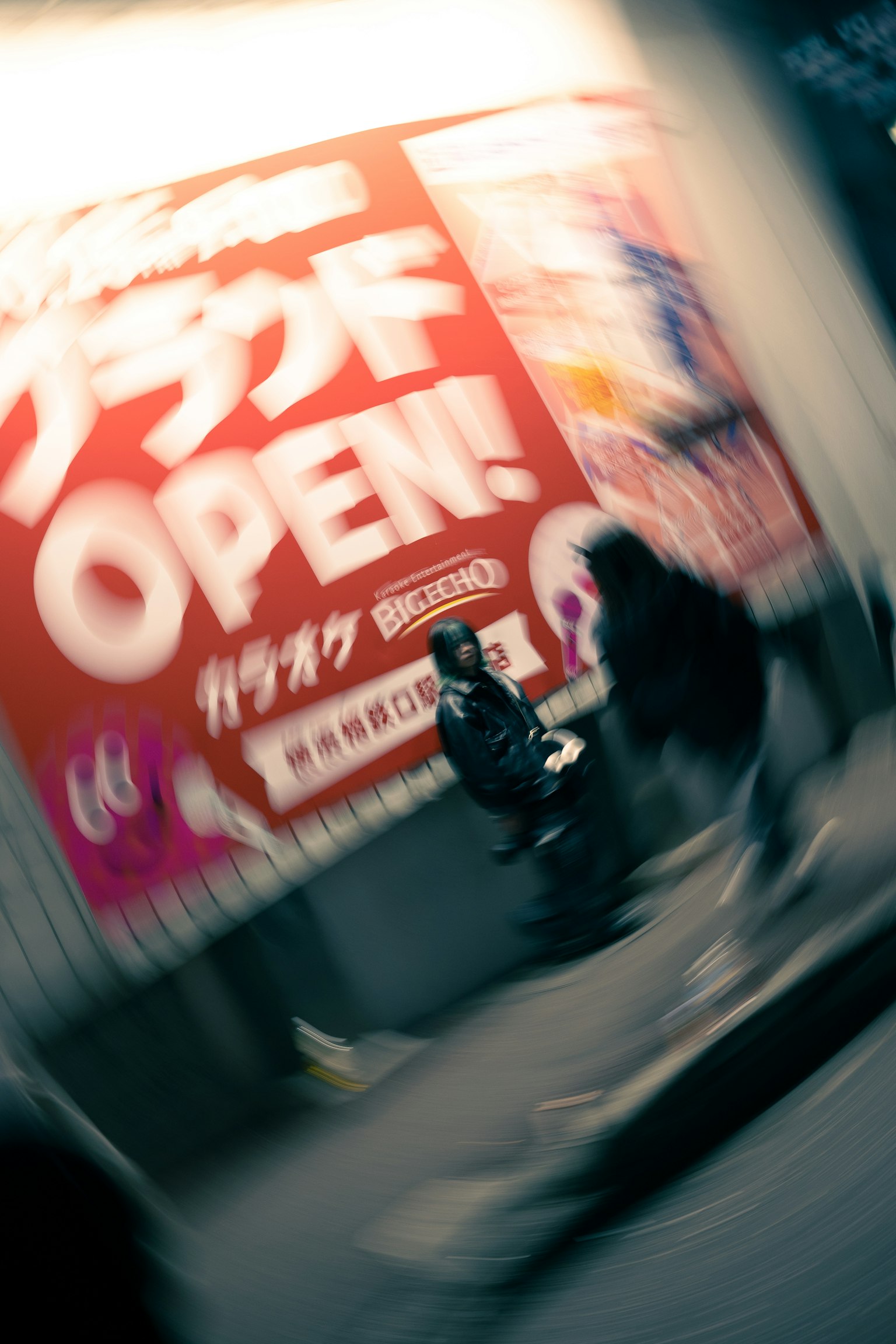 Blurred street scene featuring a large red sign with the word OPEN