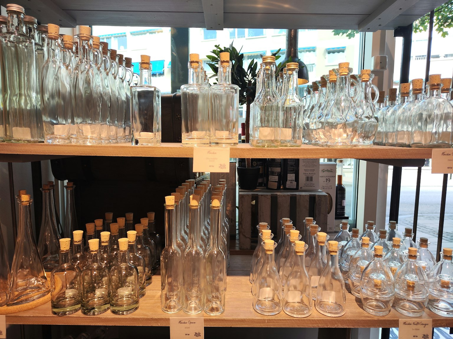 Botol kaca bening dan wadah dengan gabus yang disusun di rak kayu