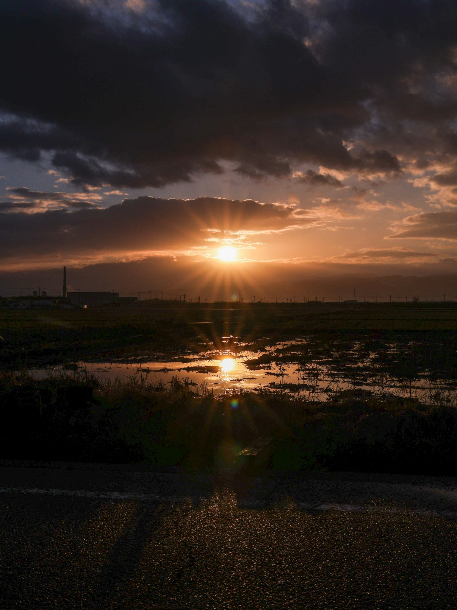 Paysage magnifique avec un coucher de soleil brillant à travers les nuages lumière se reflétant sur l'eau et champs herbeux
