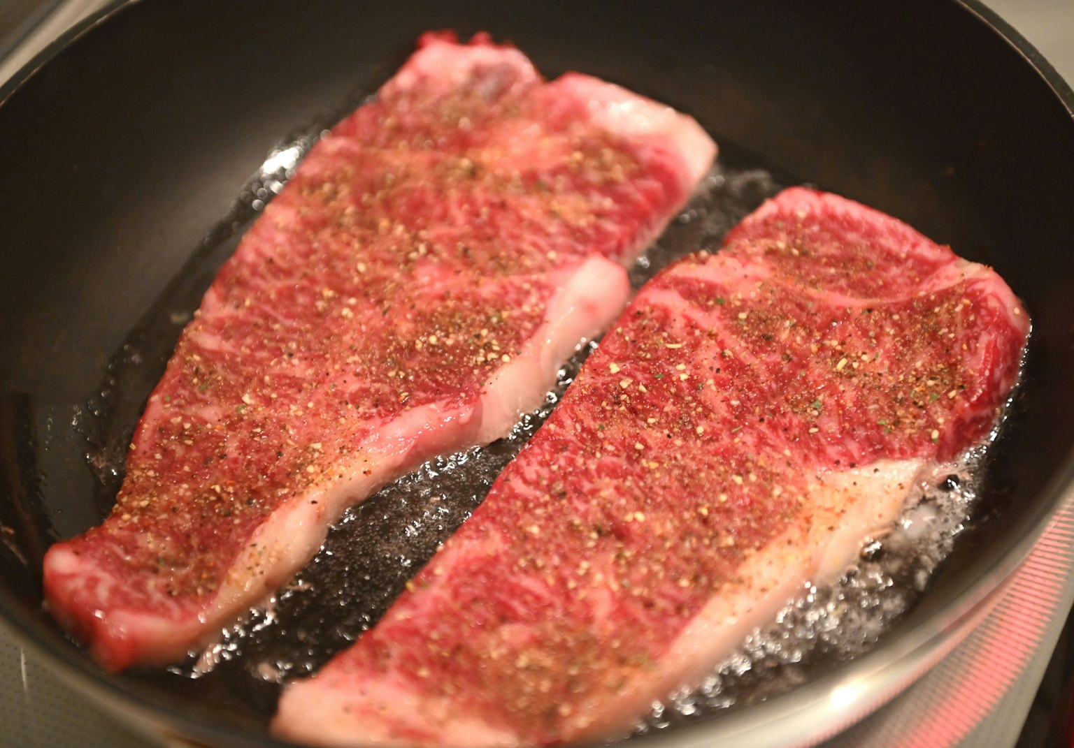 Dua steak daging sapi marmer menggelegak di wajan