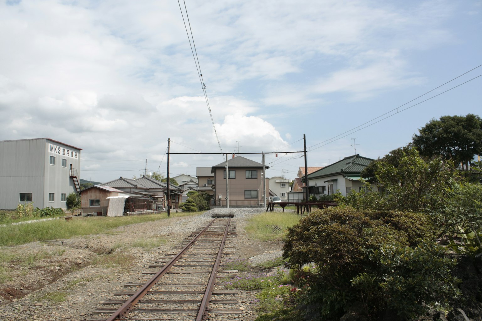 รางรถไฟในพื้นที่ที่อยู่อาศัยใต้ท้องฟ้าสีฟ้า