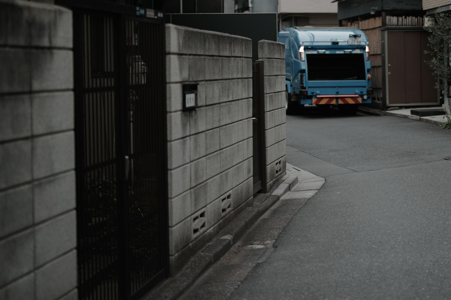 Ein blauer Müllwagen, der an einer engen Straße an der Ecke parkt