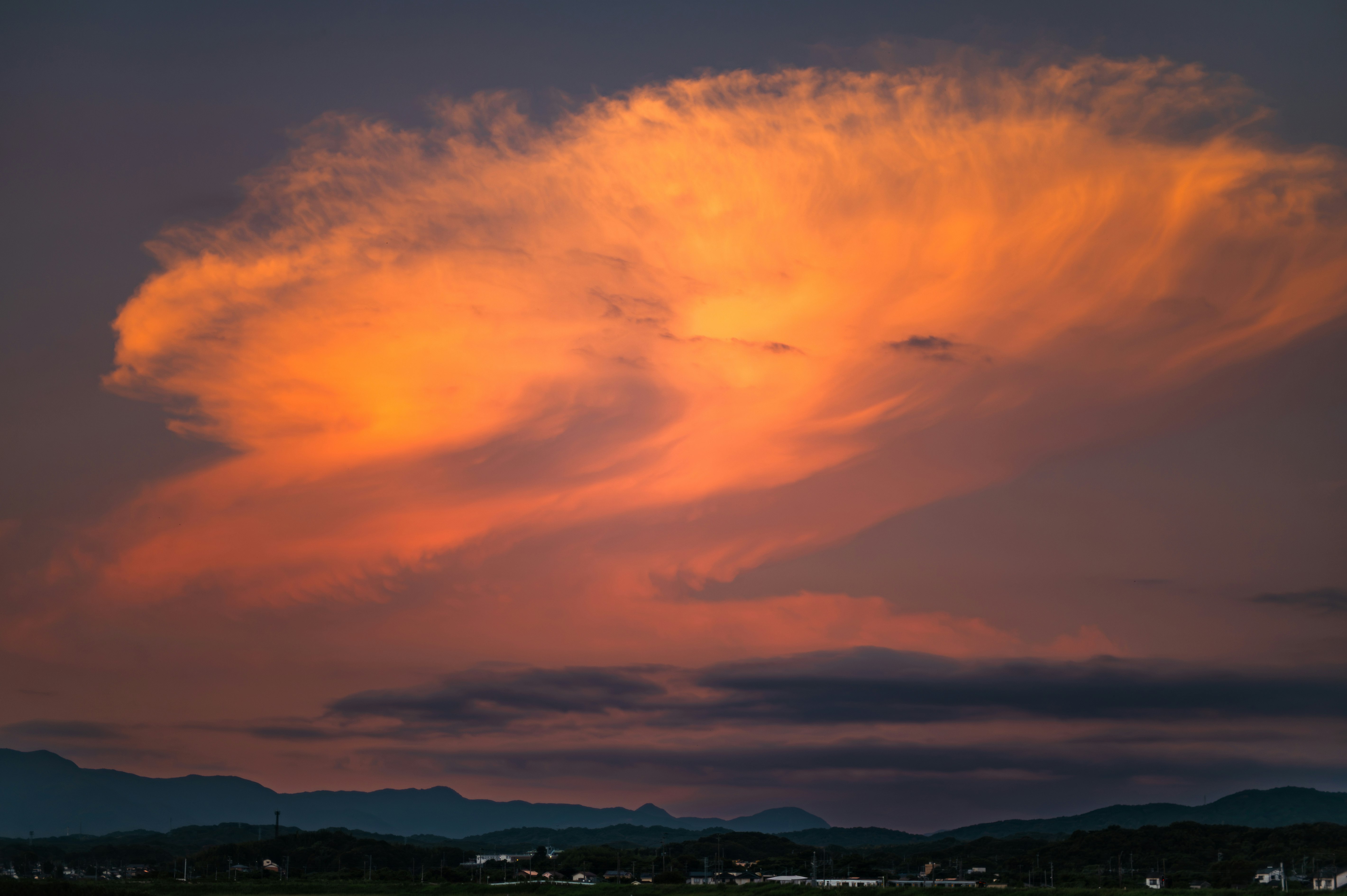 燃えるような夕焼け雲が広がる山並みの風景