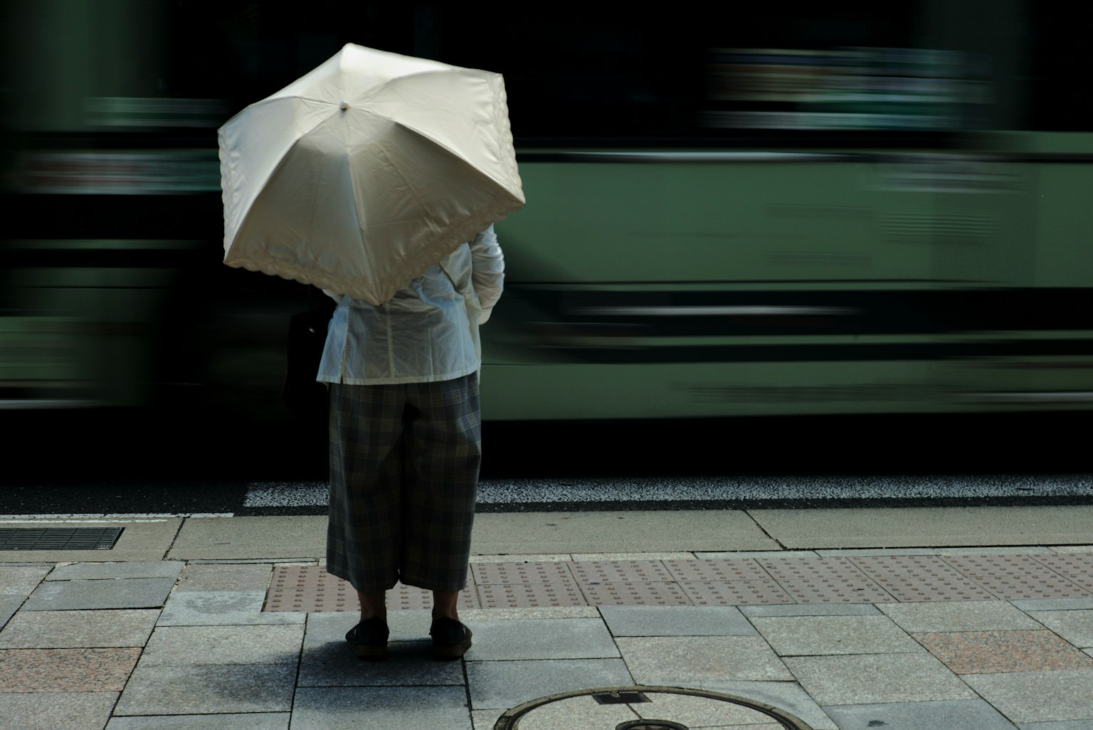 Một người cầm ô trắng đang chờ tàu đi qua