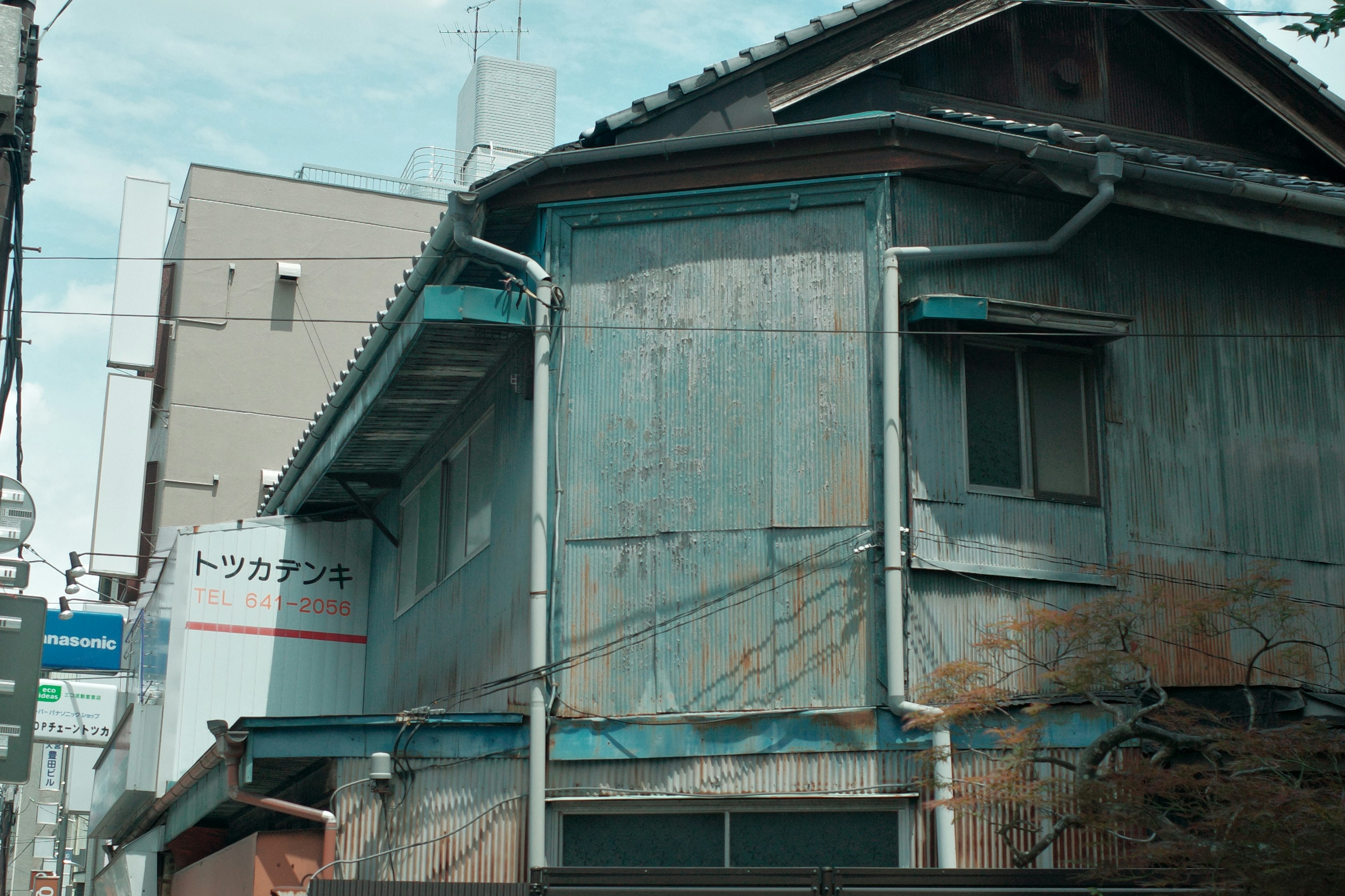 青空の下にある古い木造家屋の外壁と屋根