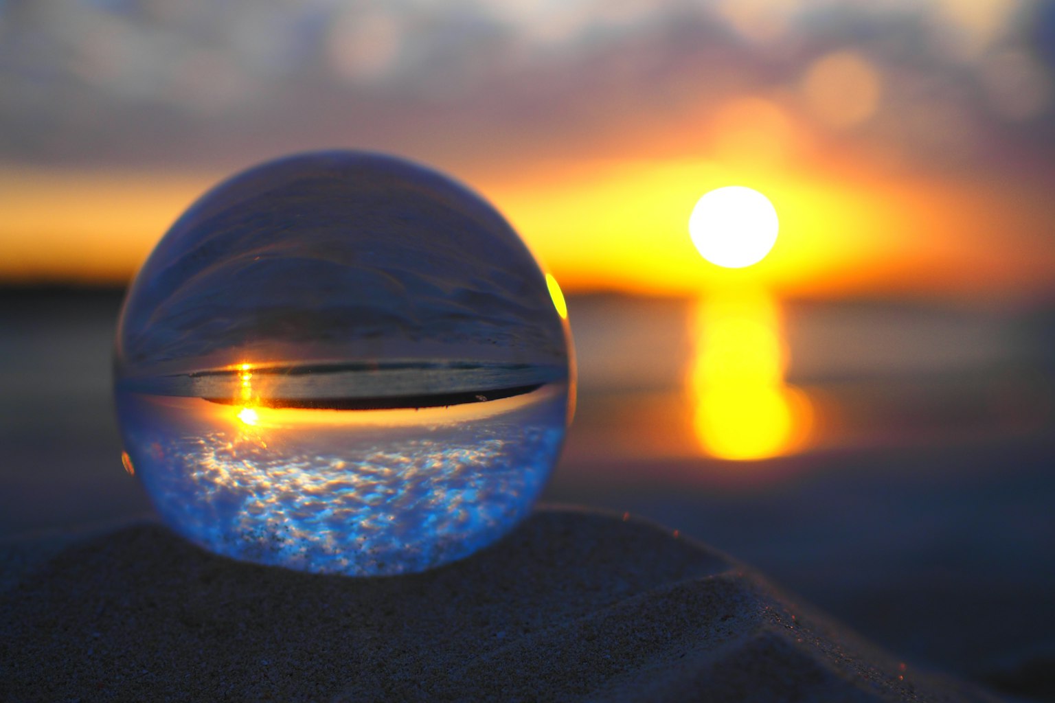 Crystal ball reflecting sunset on a sandy beach
