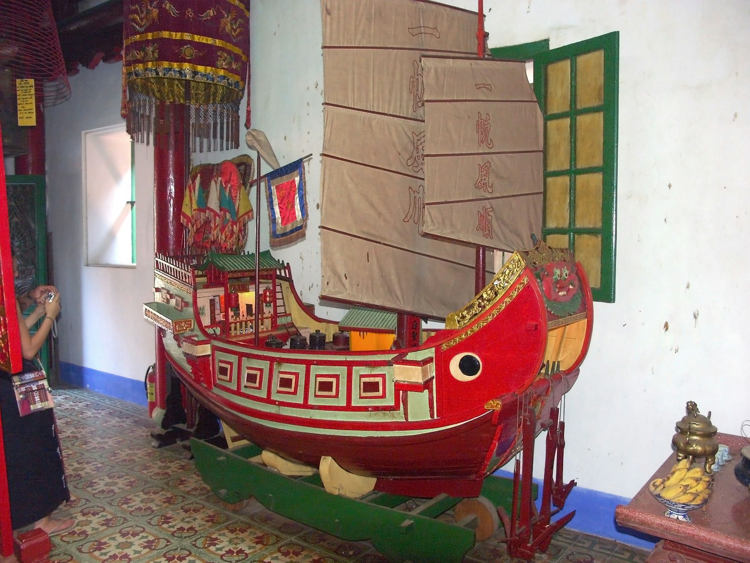 A model of a red boat displayed indoors featuring traditional design elements