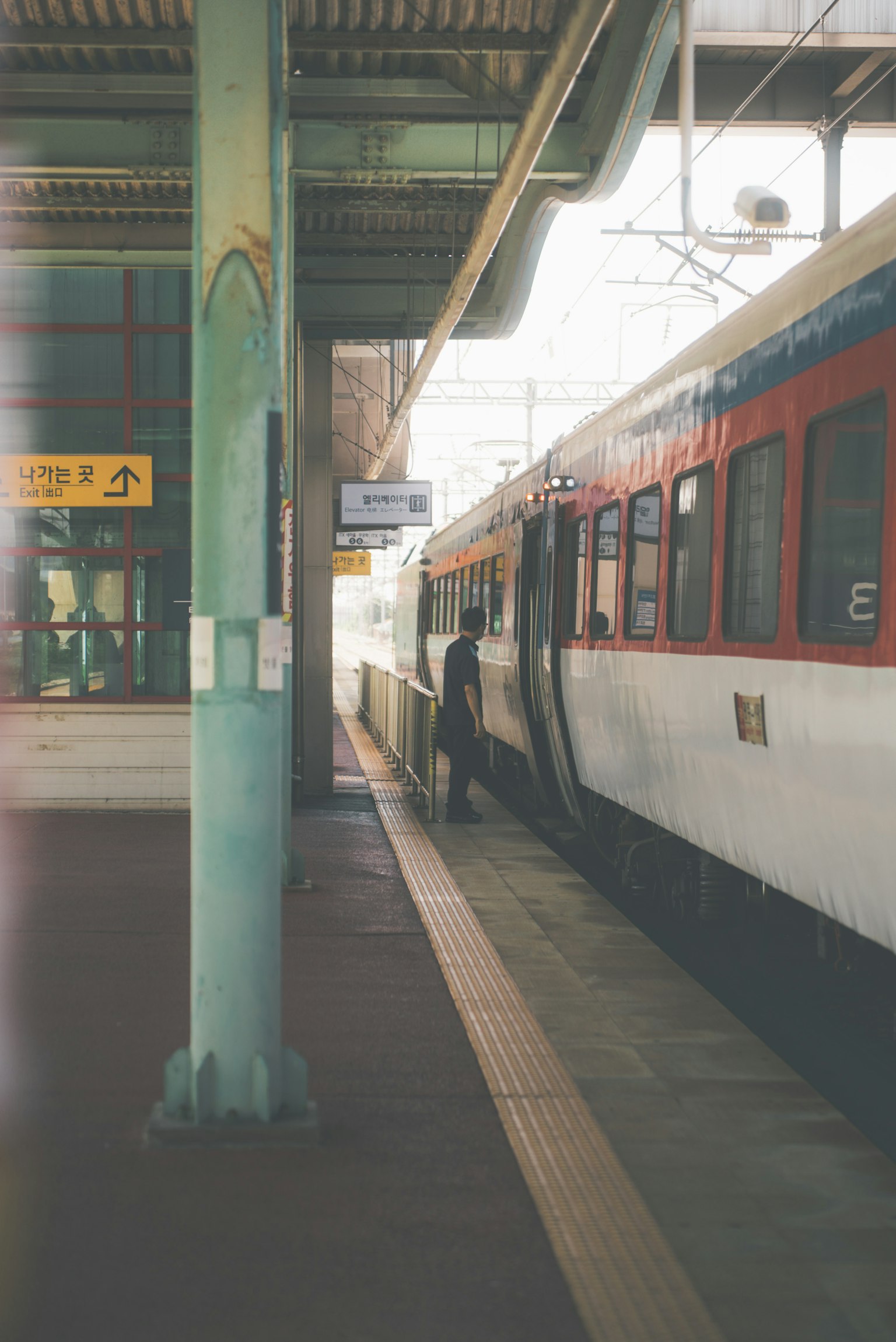 駅のプラットフォームに停車中の電車と乗客