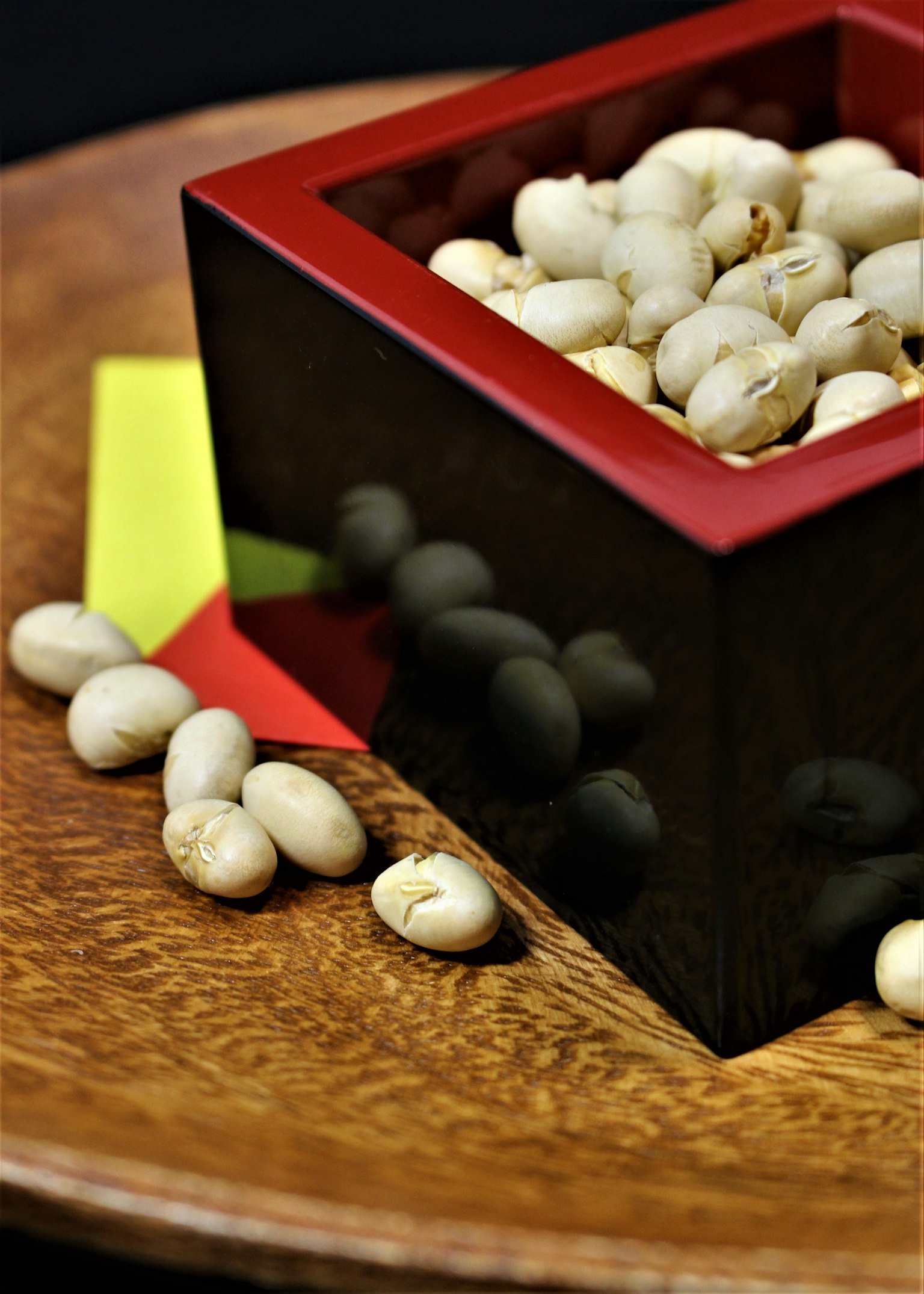 Boîte noire bordée de rouge remplie de haricots blancs sur une assiette en bois
