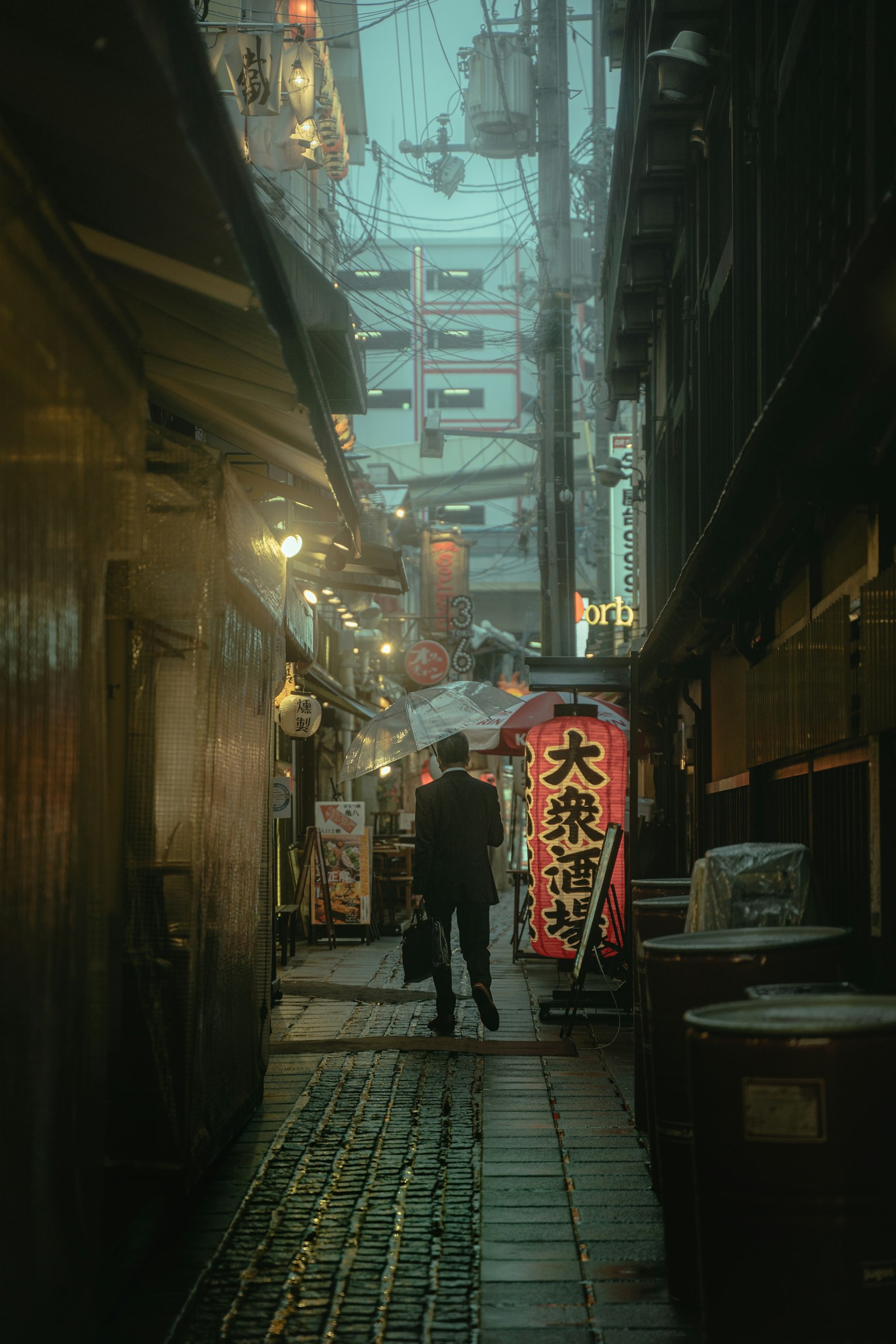 A man standing in a dim alley with a bright sign in an urban setting