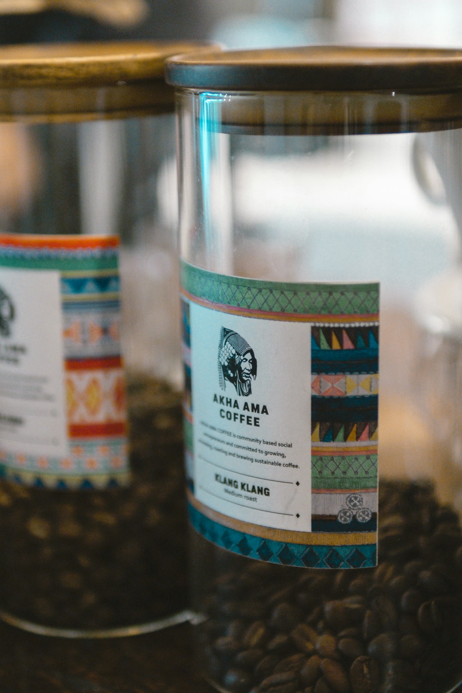 Primo piano di barattoli di vetro pieni di chicchi di caffè con etichette colorate e descrizioni del tipo di caffè