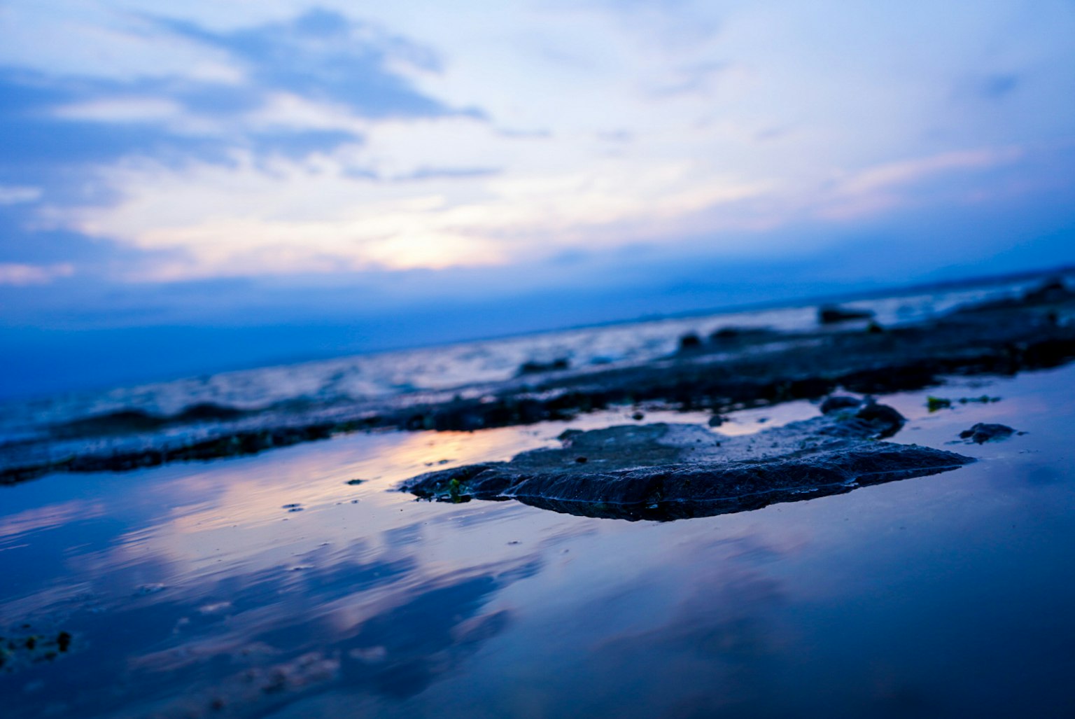 Escena de playa serena con reflejos del océano y cielo azules