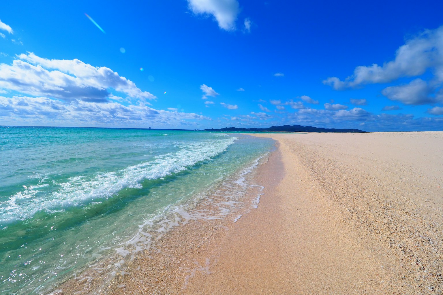 A beach scene with blue sky and gentle waves