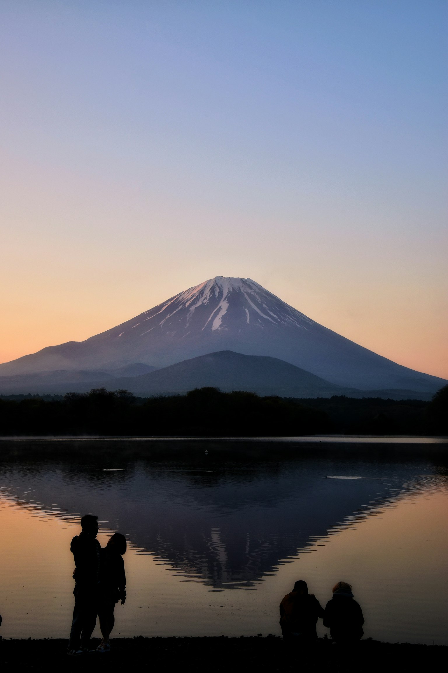 夕陽下富士山與湖面倒影中的情侶剪影