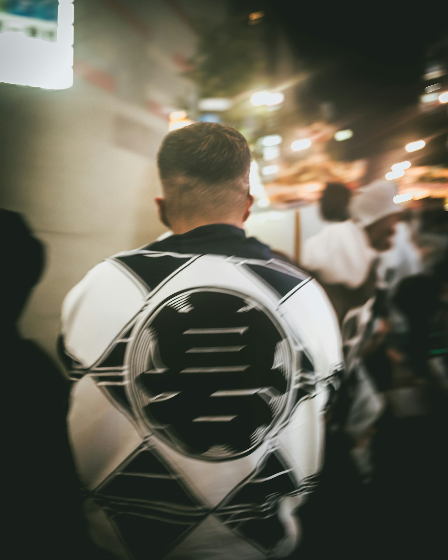 夜の街を歩く男性の後ろ姿 白と黒のデザインの服を着用