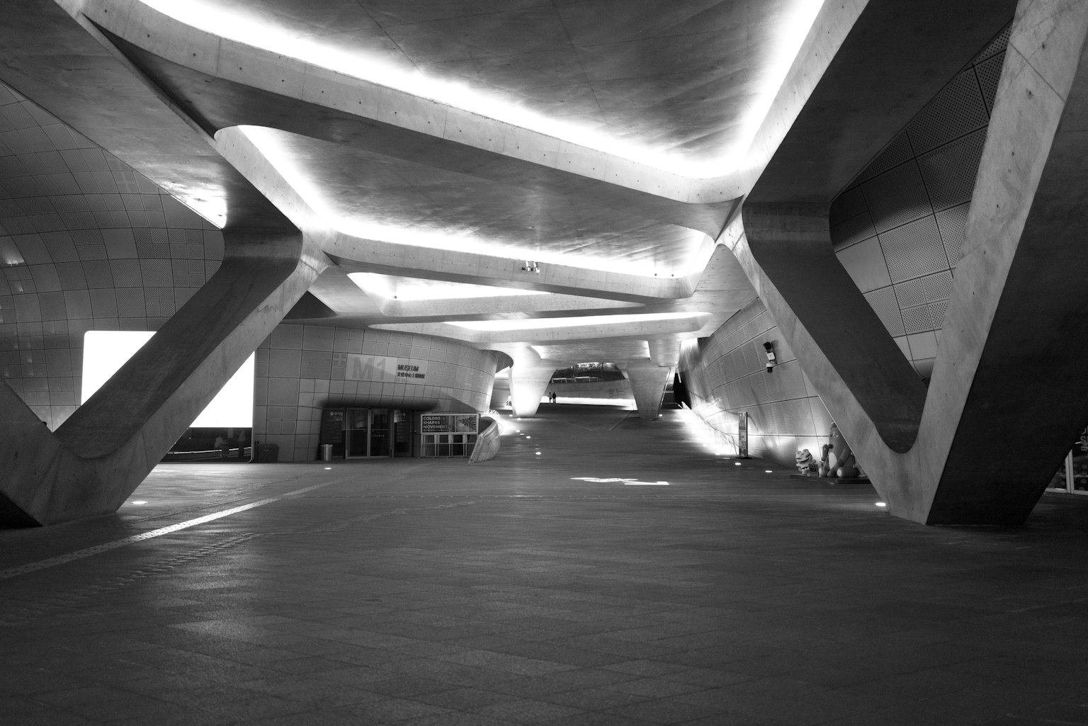 Ruang interior yang luas dengan arsitektur beton modern dan pencahayaan ambient