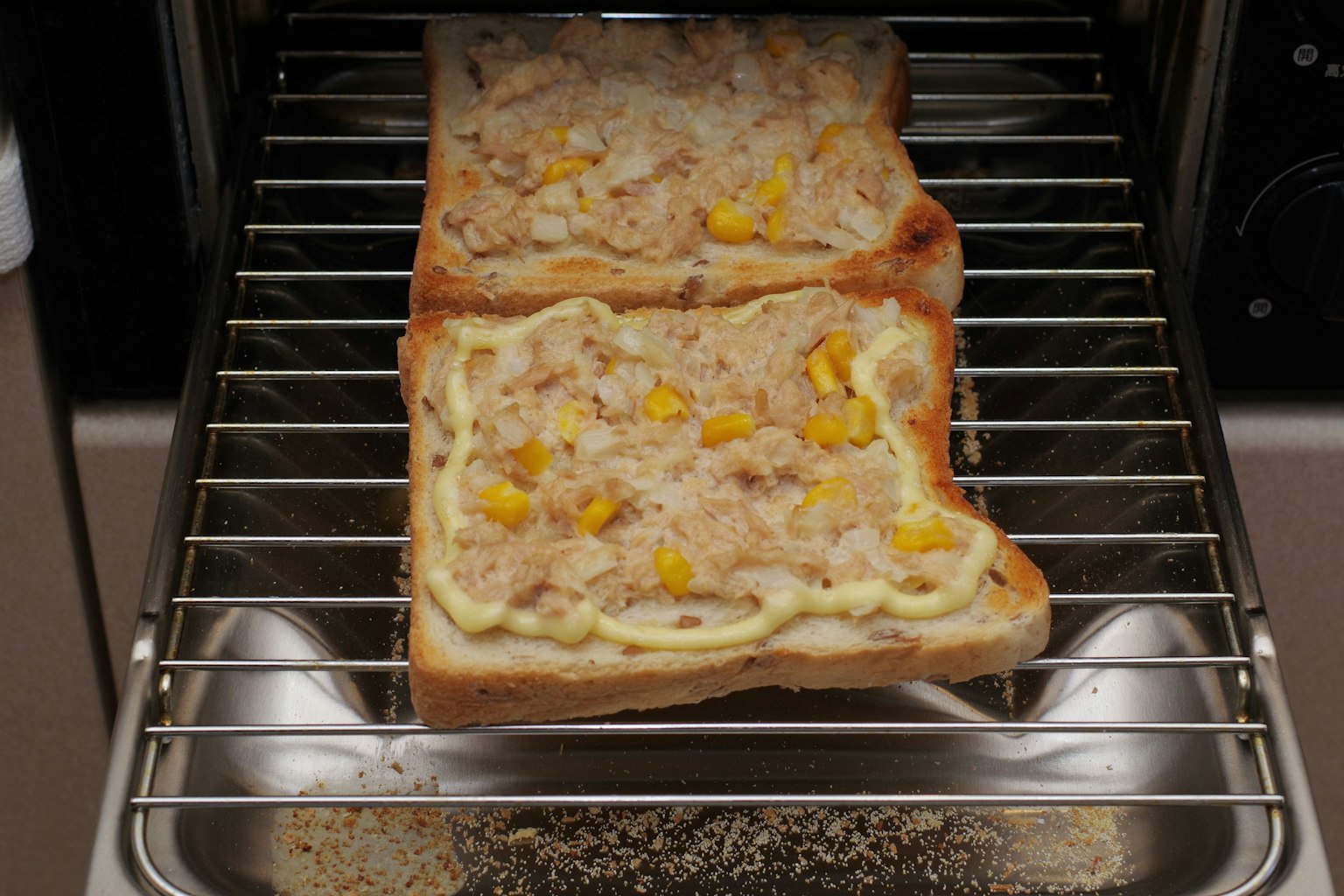 Toasted bread topped with corn and mayonnaise in a toaster