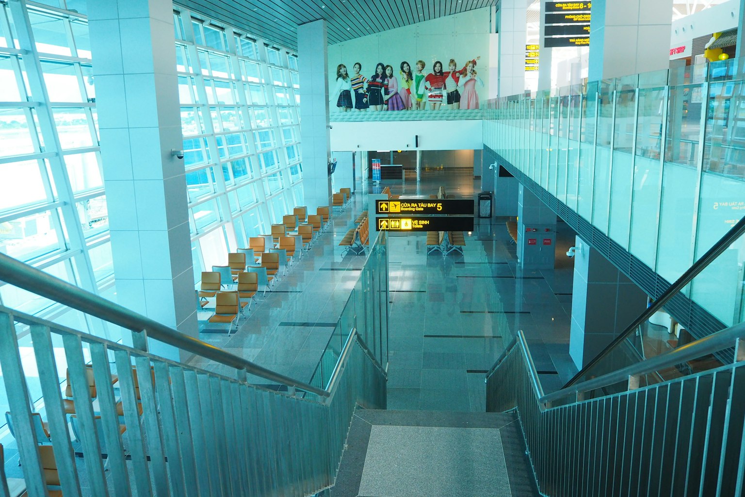 밝은 유리 벽과 금속 난간이 있는 공항 내부의 계단