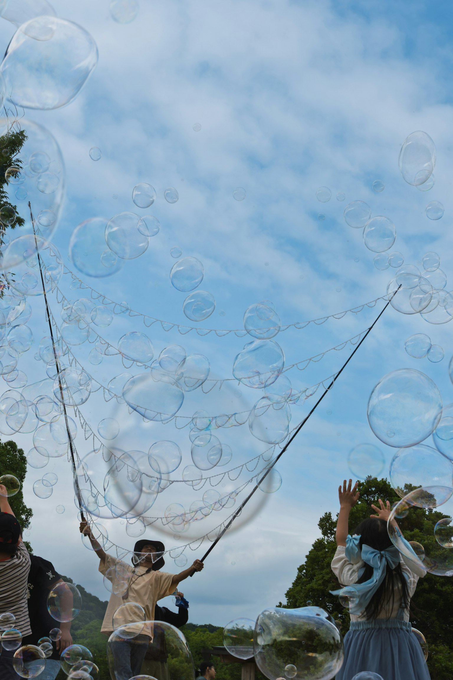 Des gens créant de grandes bulles de savon sous un ciel bleu