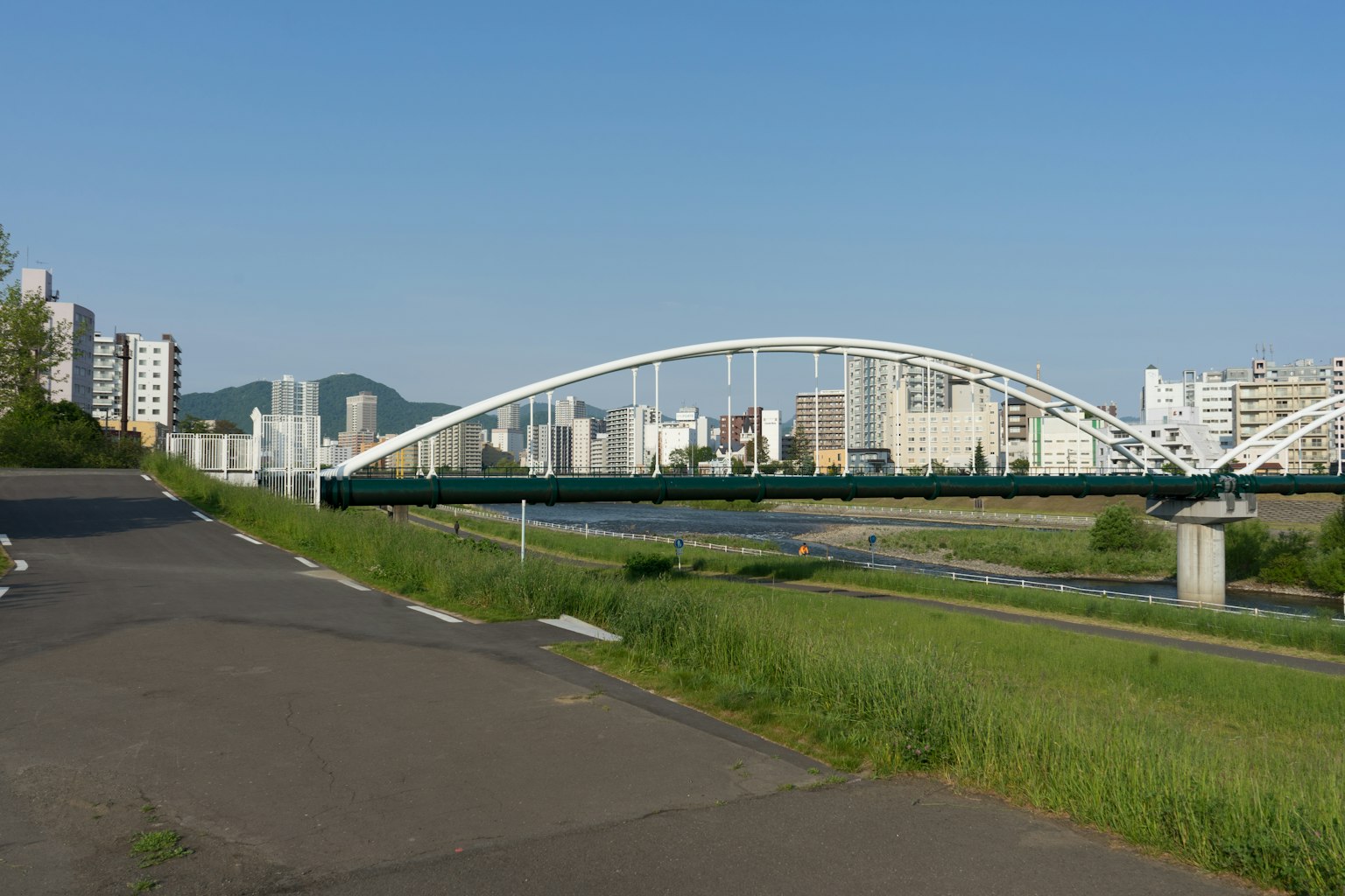 Ponte ad arco bianco sotto un cielo blu con edifici circostanti