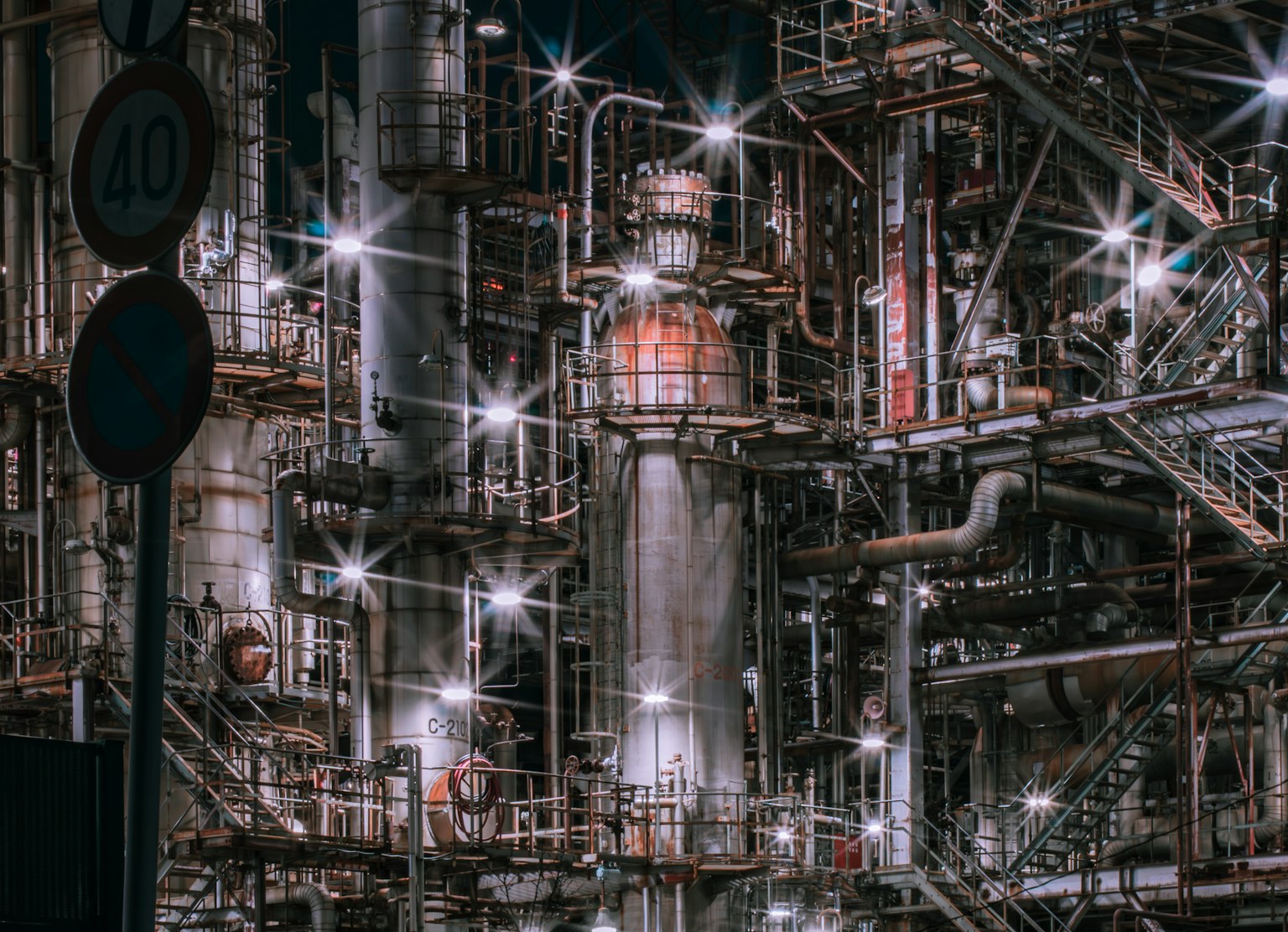 夜の工場の複雑なパイプとタンクの構造が輝いている