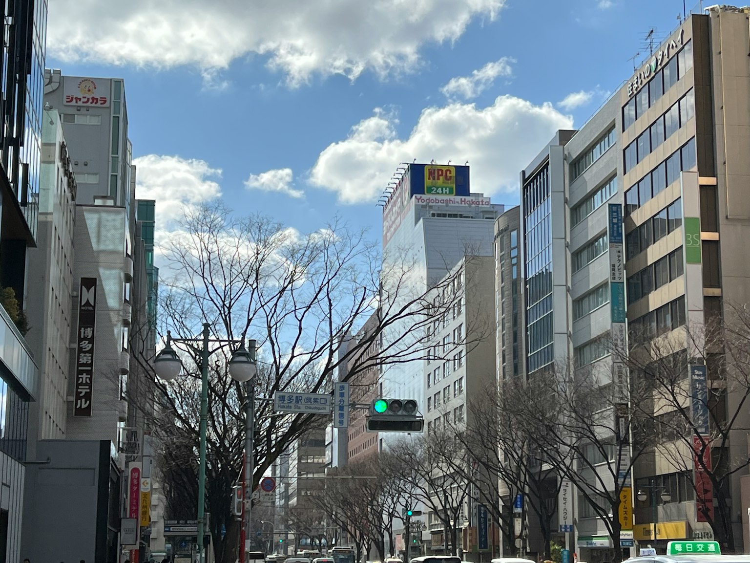 Urban landscape on a sunny day featuring tall buildings and blue sky with bare trees