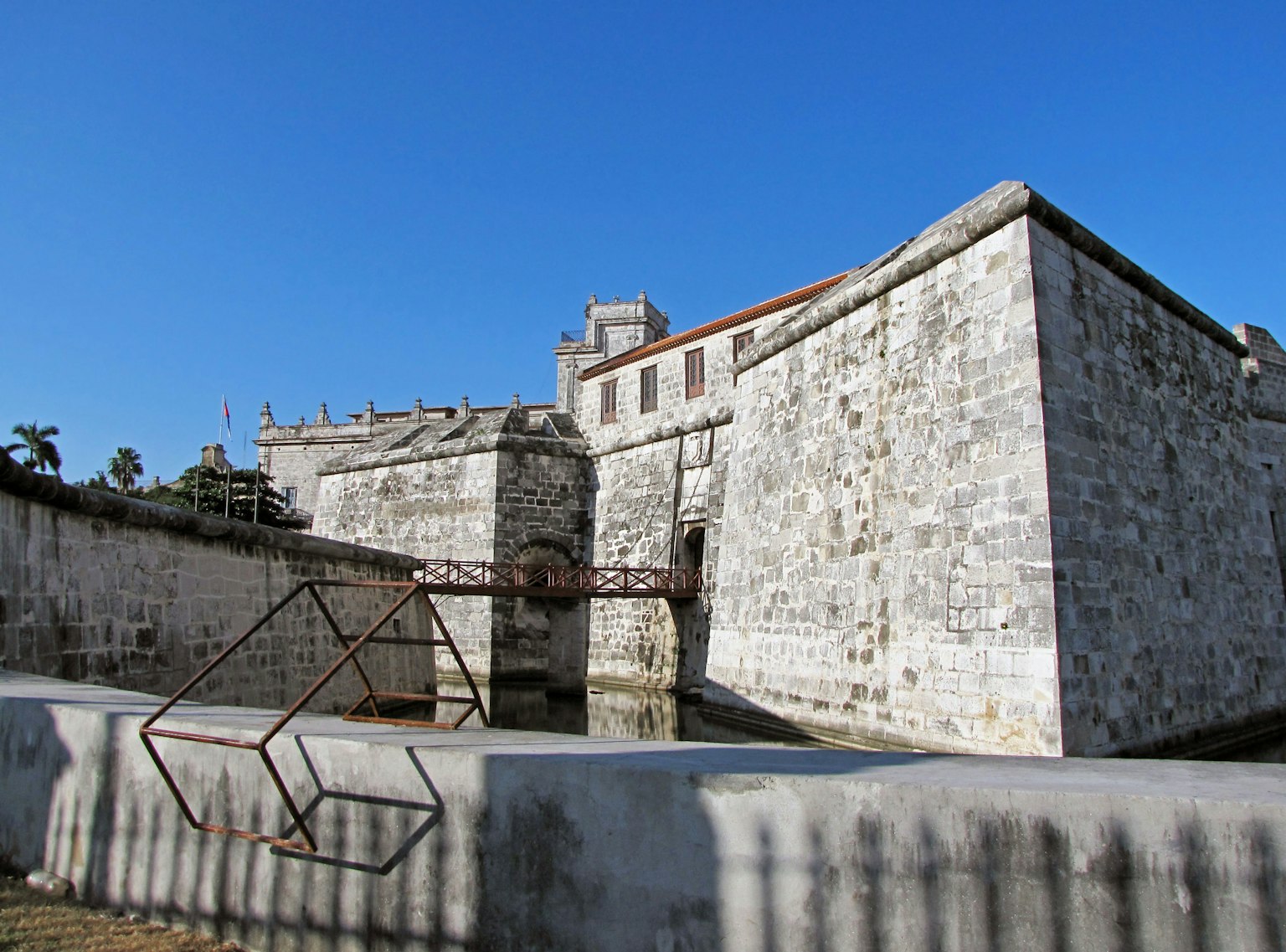 Antica fortezza in pietra sotto un cielo blu con una struttura metallica in primo piano