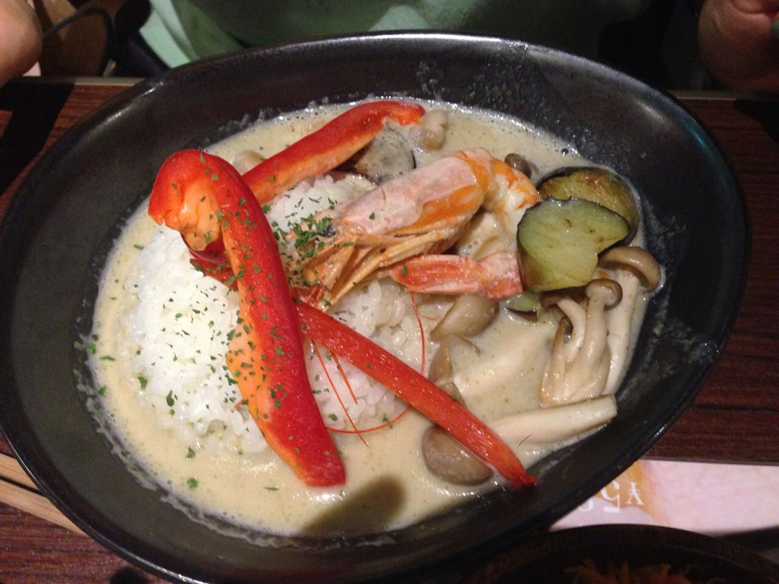 A creamy soup dish topped with shrimp and vegetables