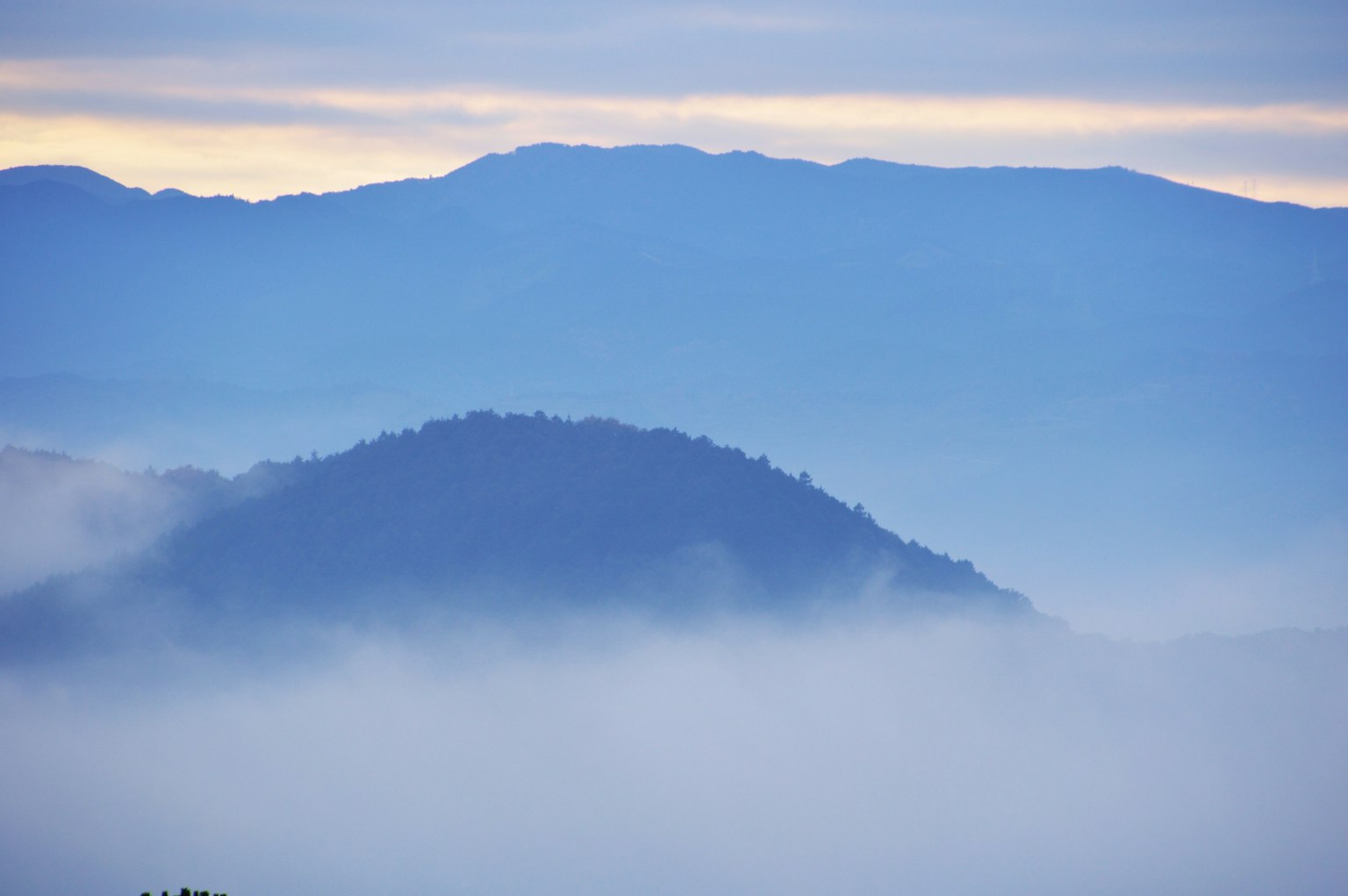 Paysage de montagnes enveloppées de brume avec un ciel bleu et des sommets lointains