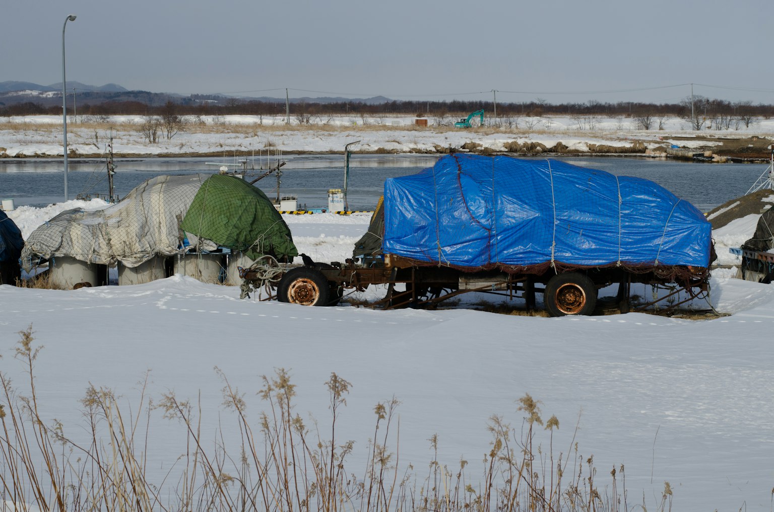Snow-covered landscape with trailers covered in blue tarps