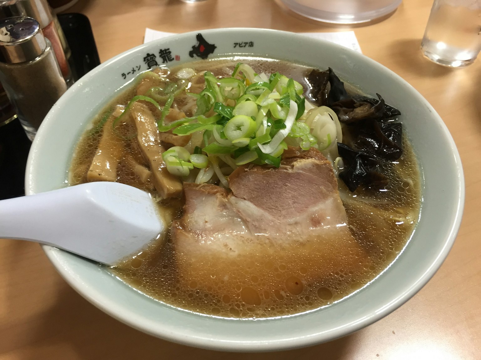 一碗拉面，上面放着叉烧、青葱和黑木耳