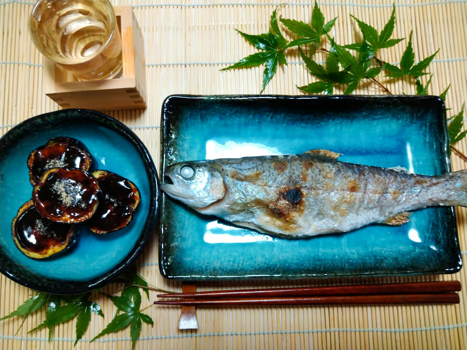 烤鱼与配菜在蓝色盘子中呈现于日本餐饮环境中