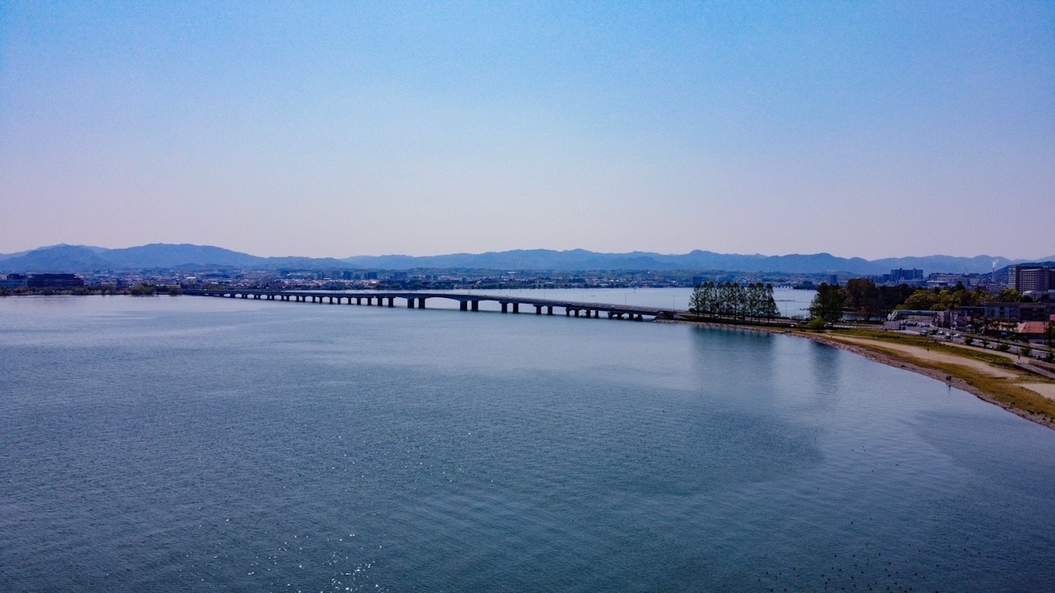 Malersicher Blick auf eine Brücke über ruhiges Wasser unter blauem Himmel