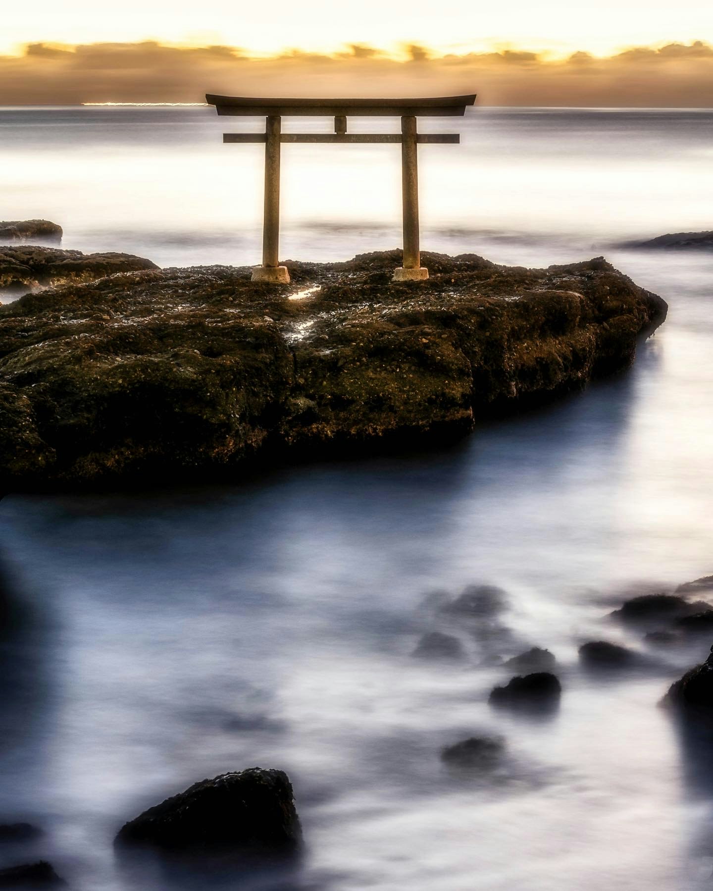 鳥居と岩場の海岸に広がる夕景
