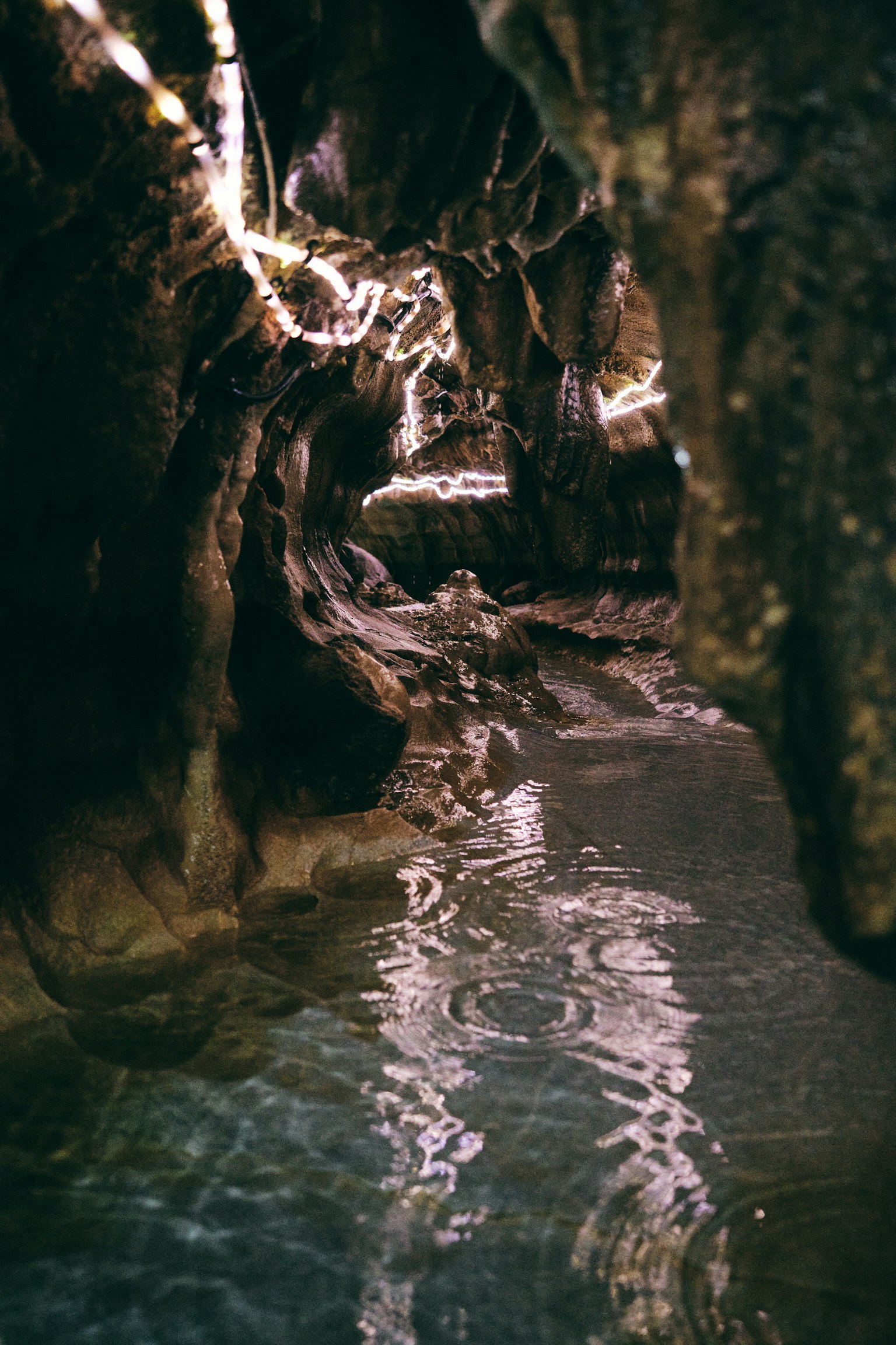 Dark cave interior with flowing water and reflections