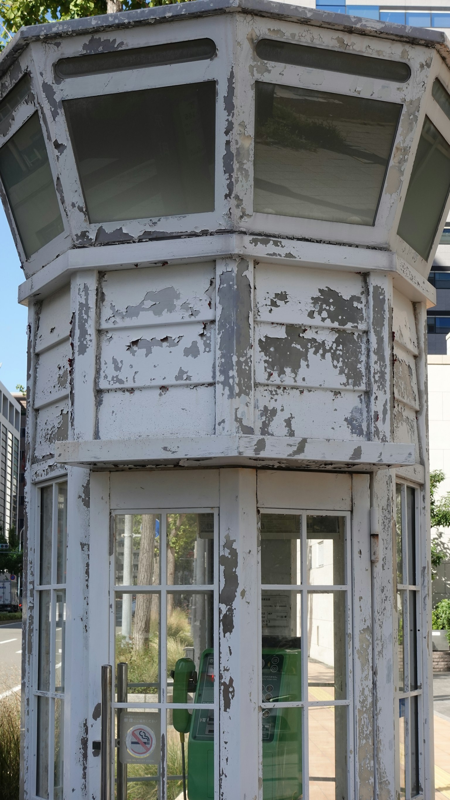 Cabina telefónica blanca antigua con pintura descascarada