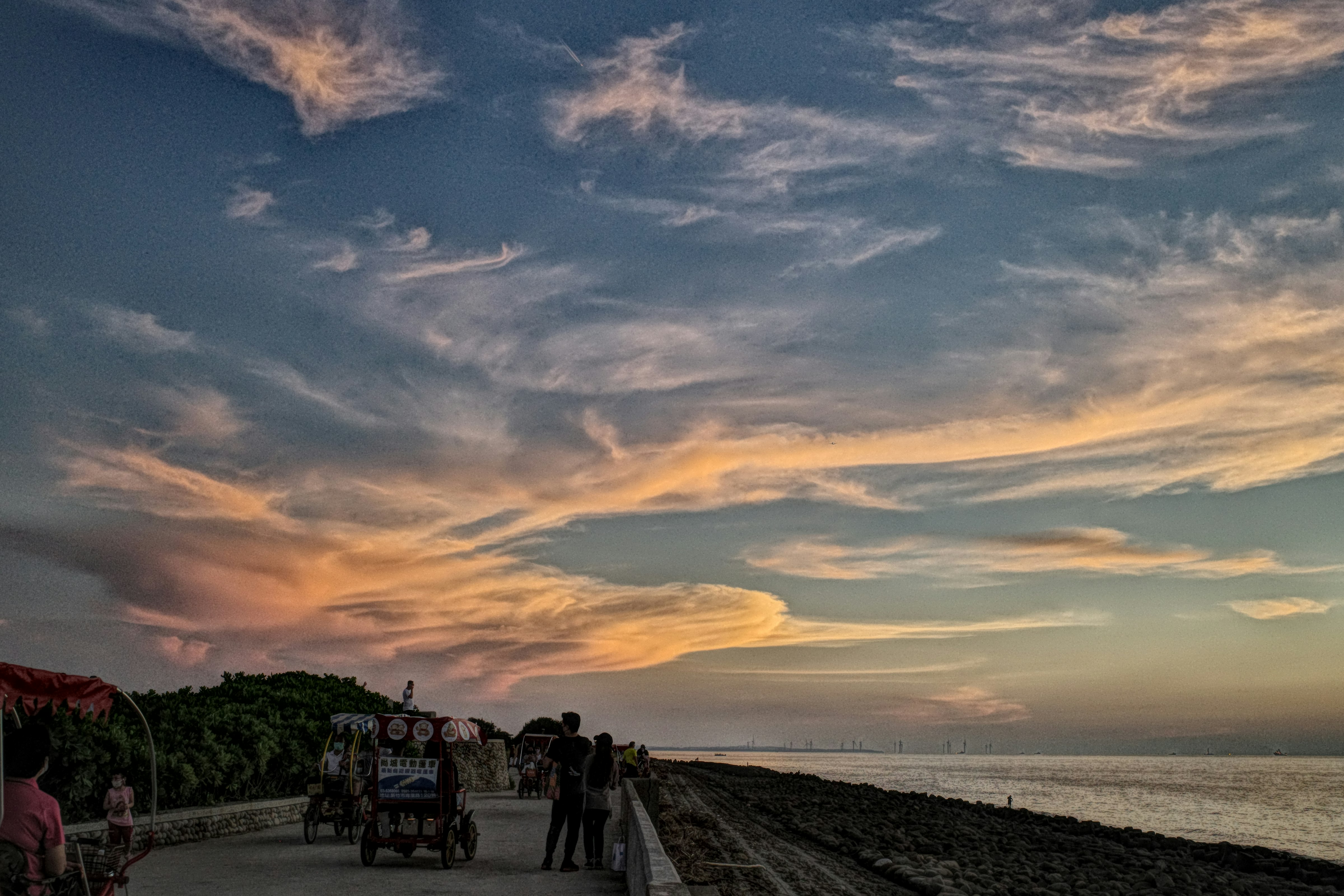 夕暮れの海辺を歩く人々と屋台の並ぶ通り