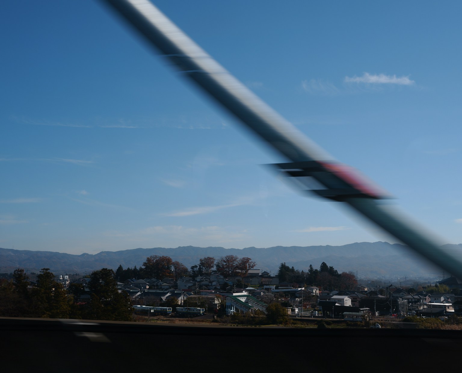 Urban landscape with blue sky and mountains in the background featuring a blurred train track