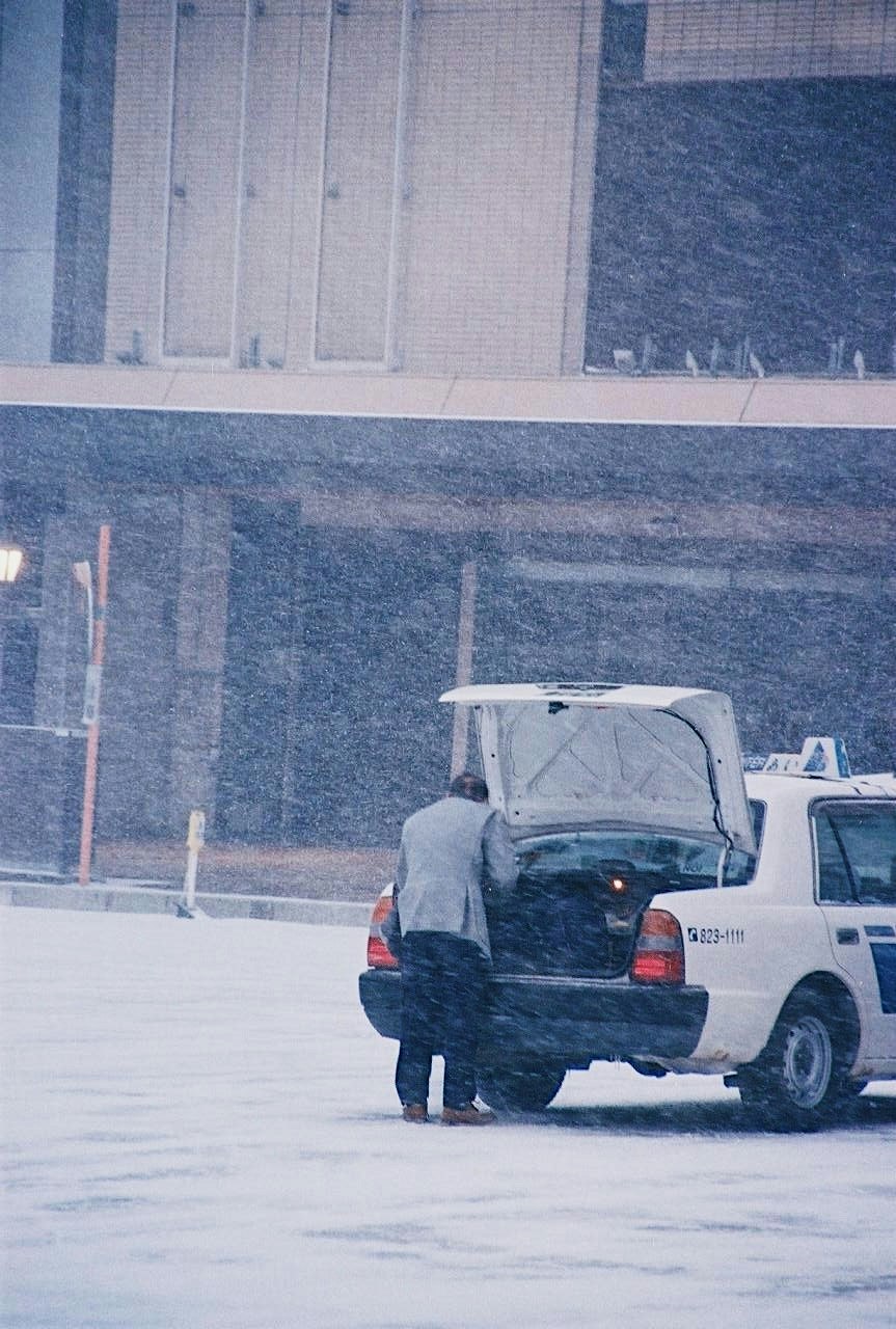 Camion e veicolo di lavoro coperti di neve durante una forte nevicata