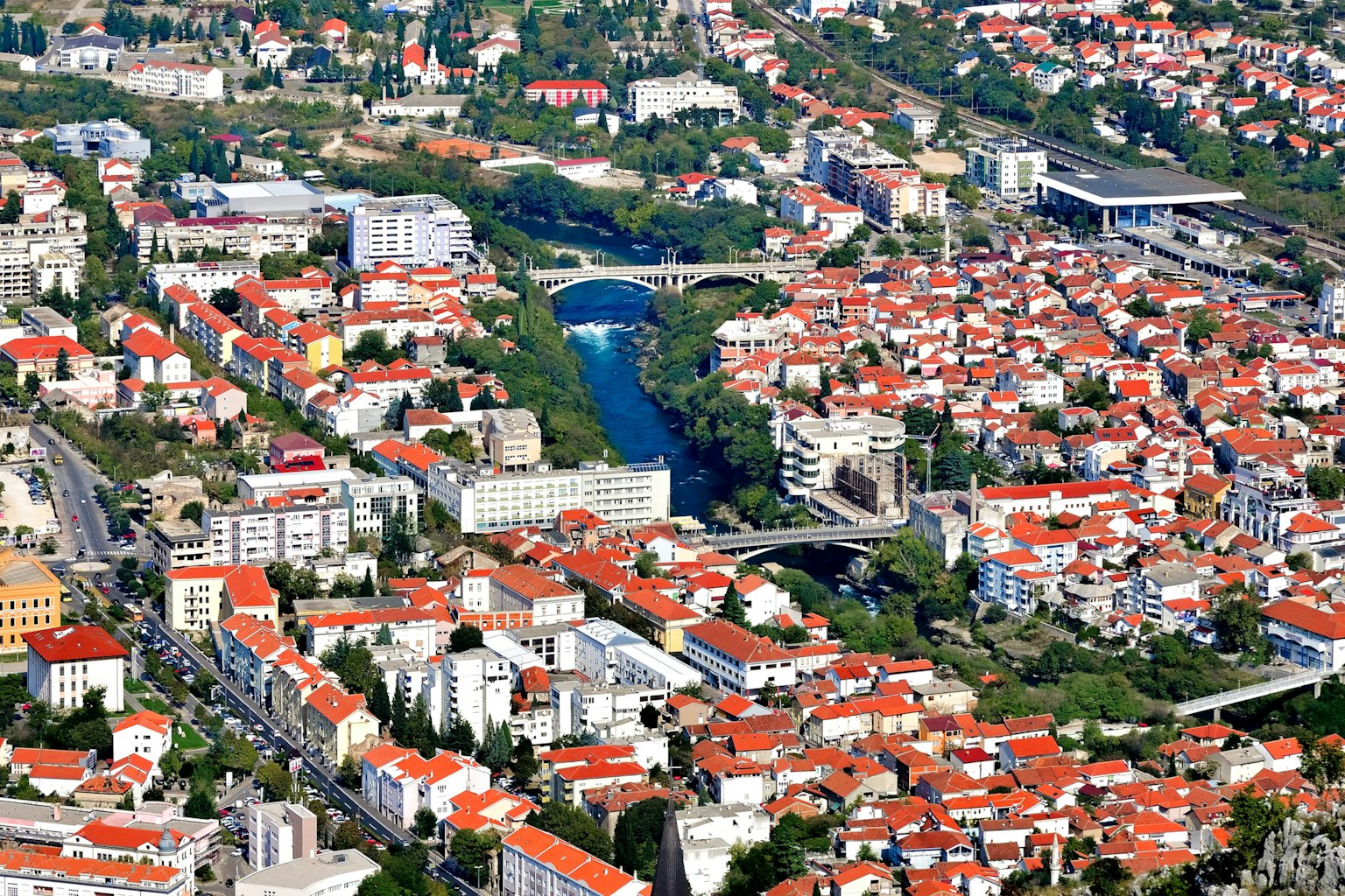 Luftaufnahme einer Stadt mit roten Dächern und einem Fluss