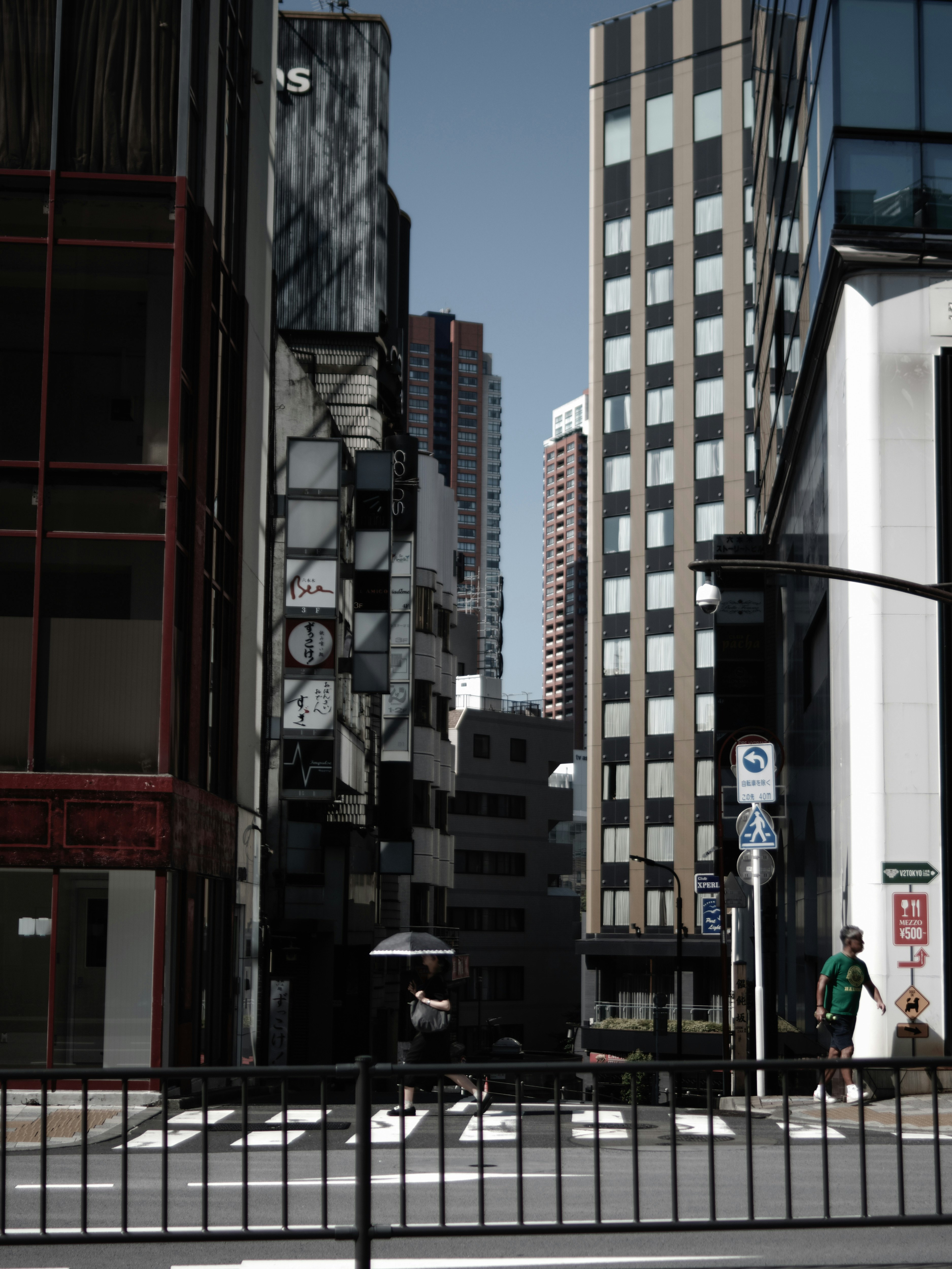 ビルの間の高架下に続く街路の坂道風景