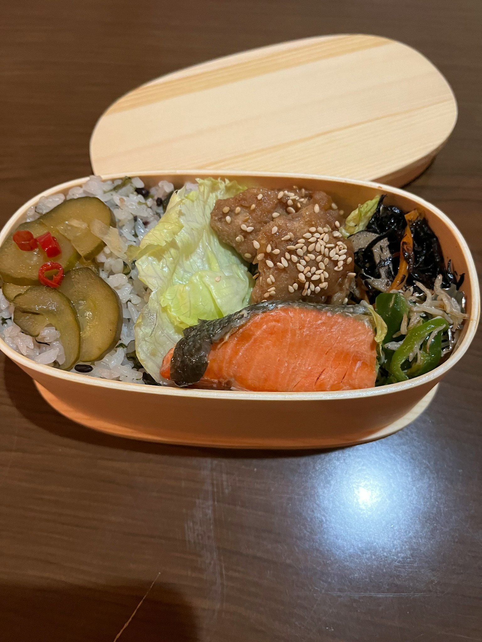 Caja de bento llena de salmón, verduras, arroz y encurtidos
