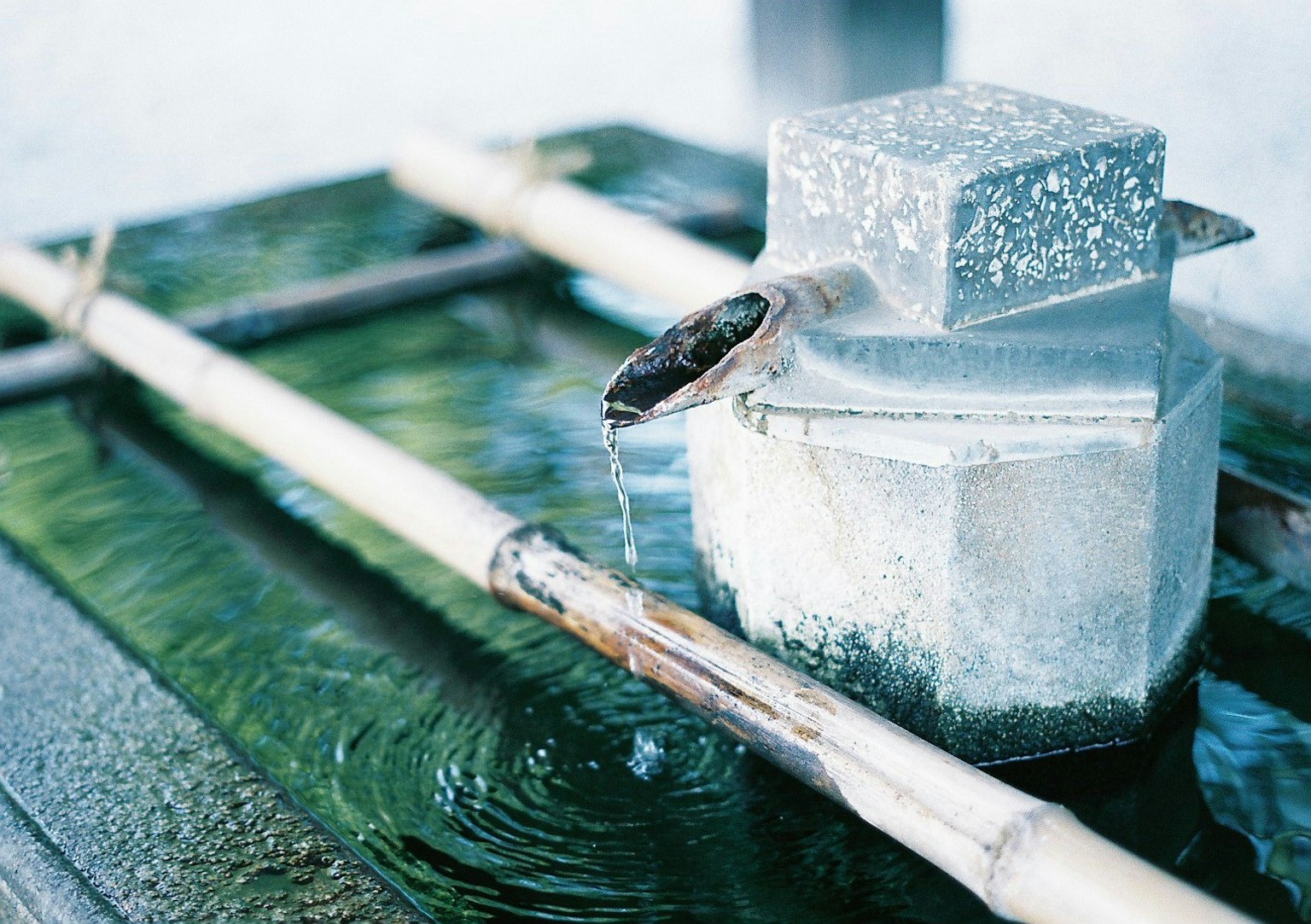 Một đặc điểm nước yên bình với bể kim loại vuông và ống tre tạo ra gợn sóng trong nước