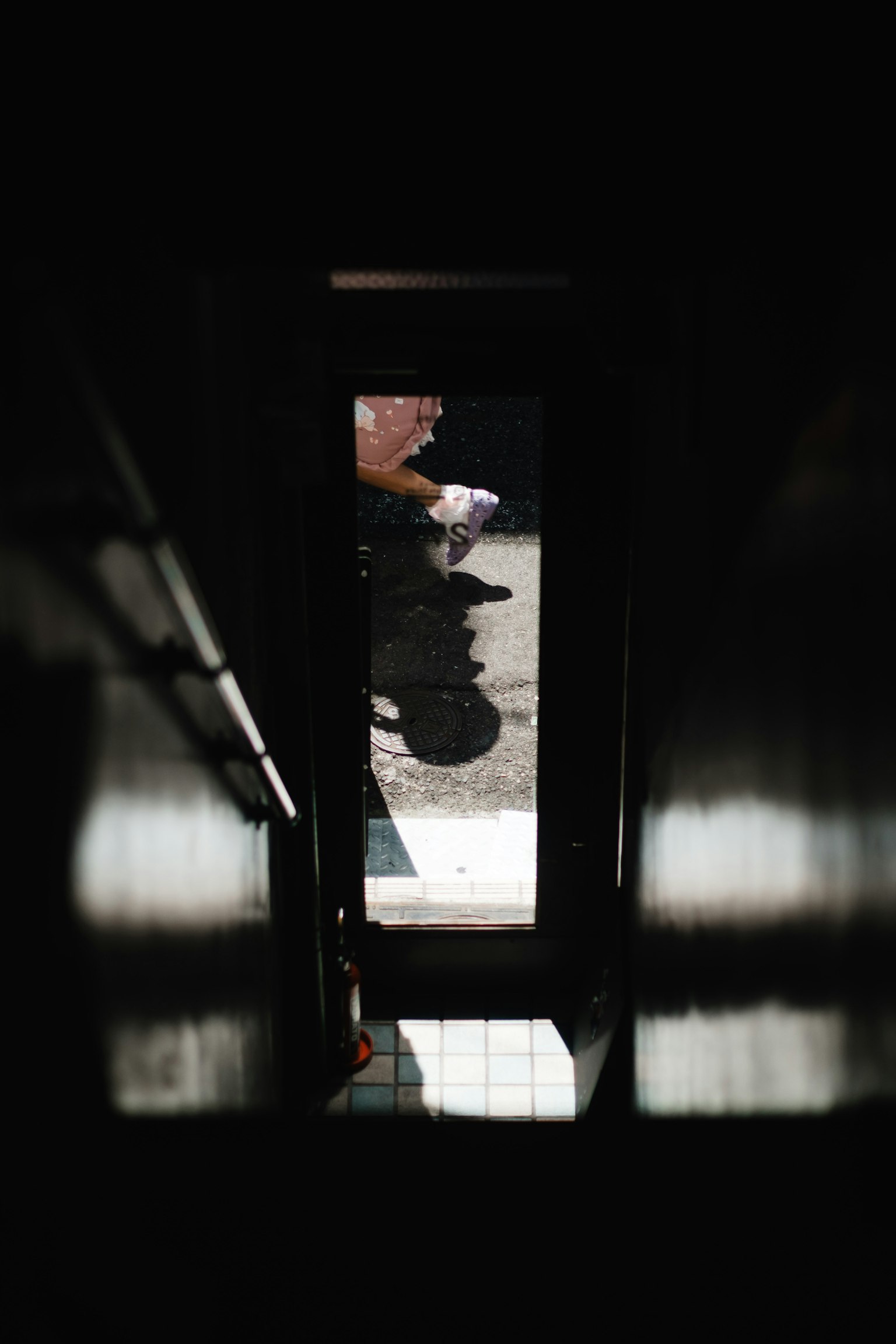 View from below stairs showing outdoor scene and shadow of a person