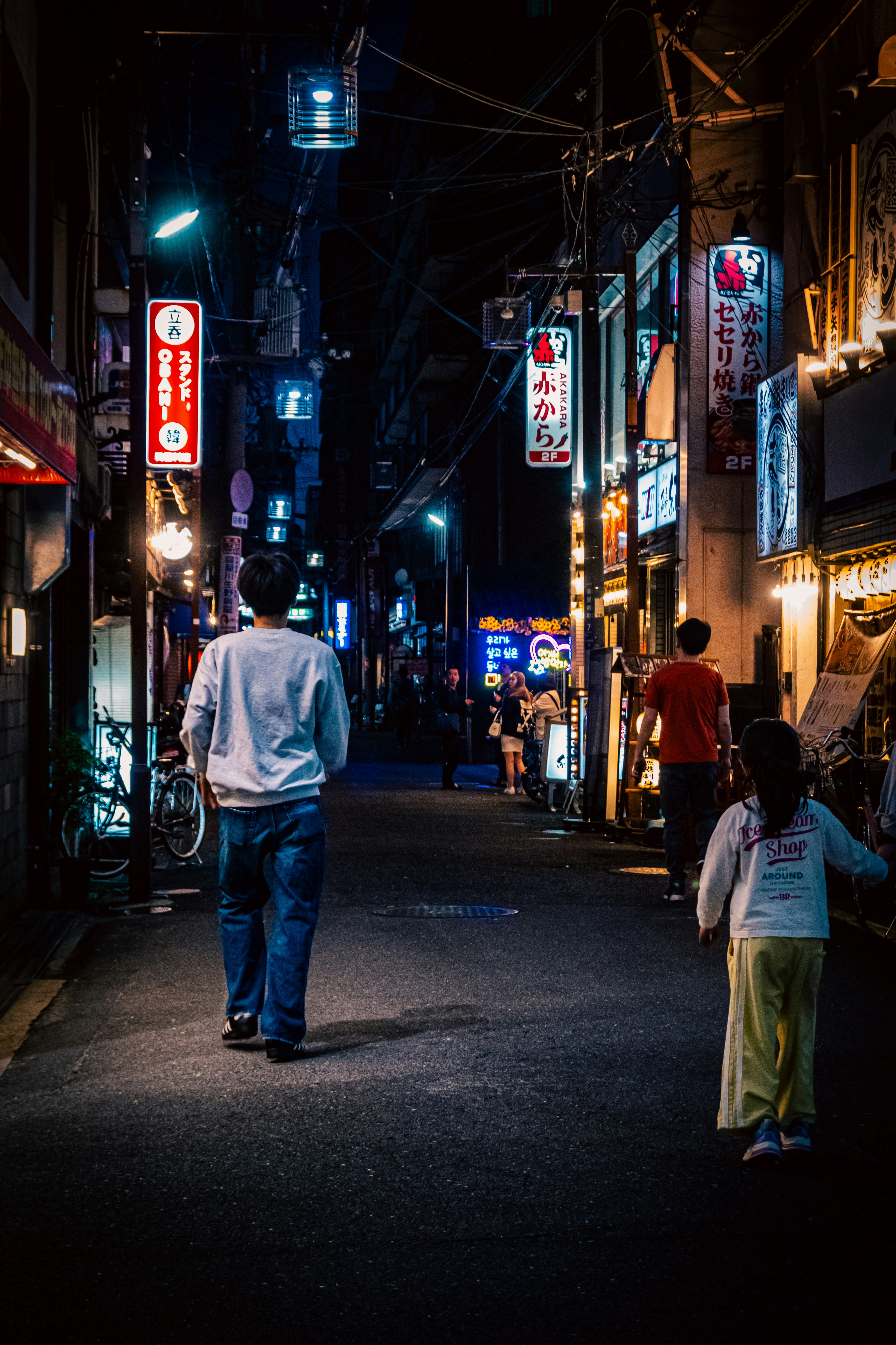 ネオン看板が並ぶ夜の路地で歩く人々のある商店街の通り