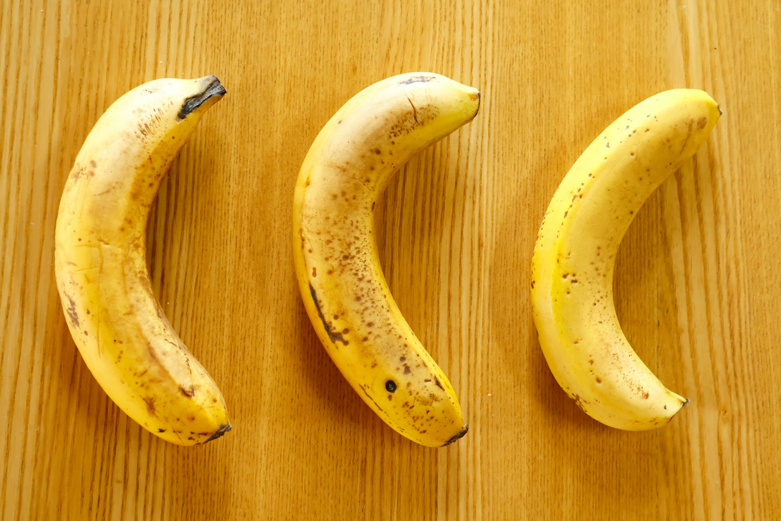 Trois bananes disposées sur une table en bois
