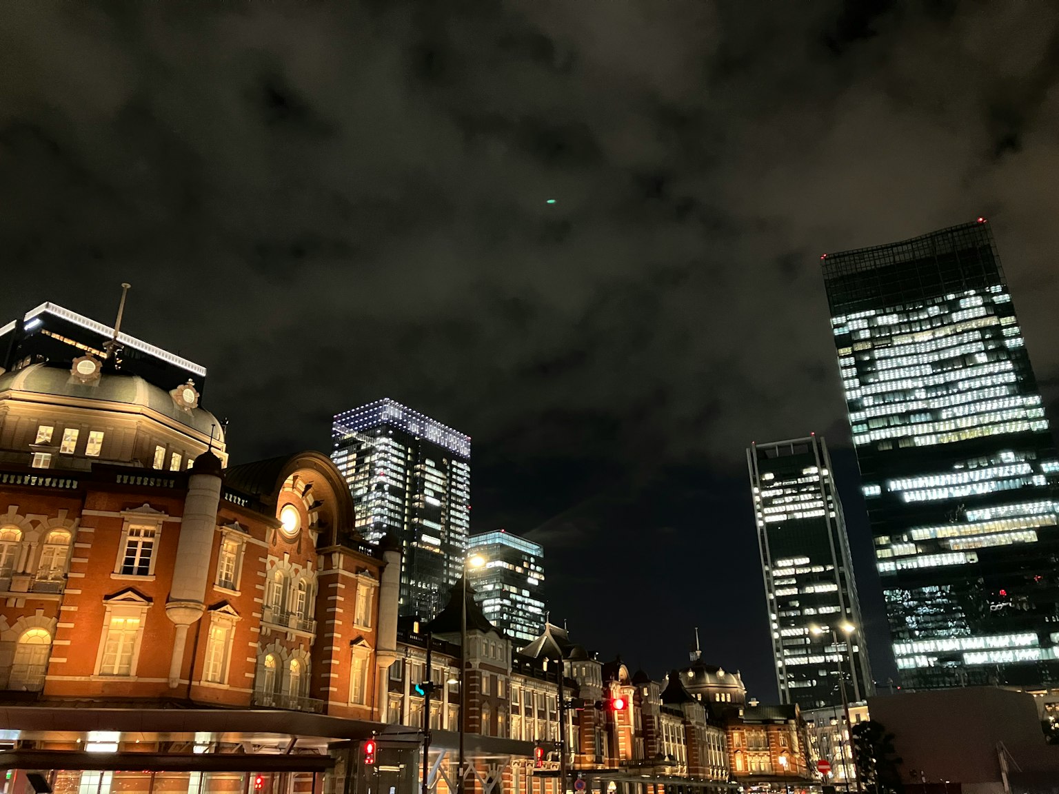 Pemandangan kota malam dengan gedung pencakar langit yang diterangi dan langit berawan